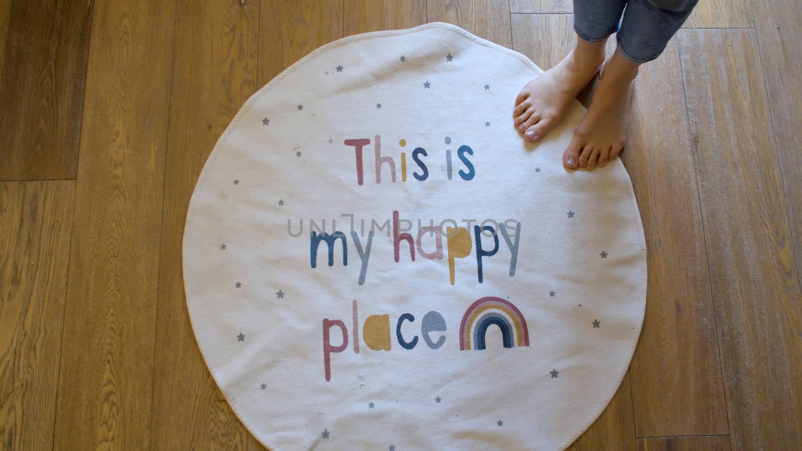 Round carpet with the inscription - this is my happy place. Personal space symbol. Woman barefoot standing on the edge, top view
