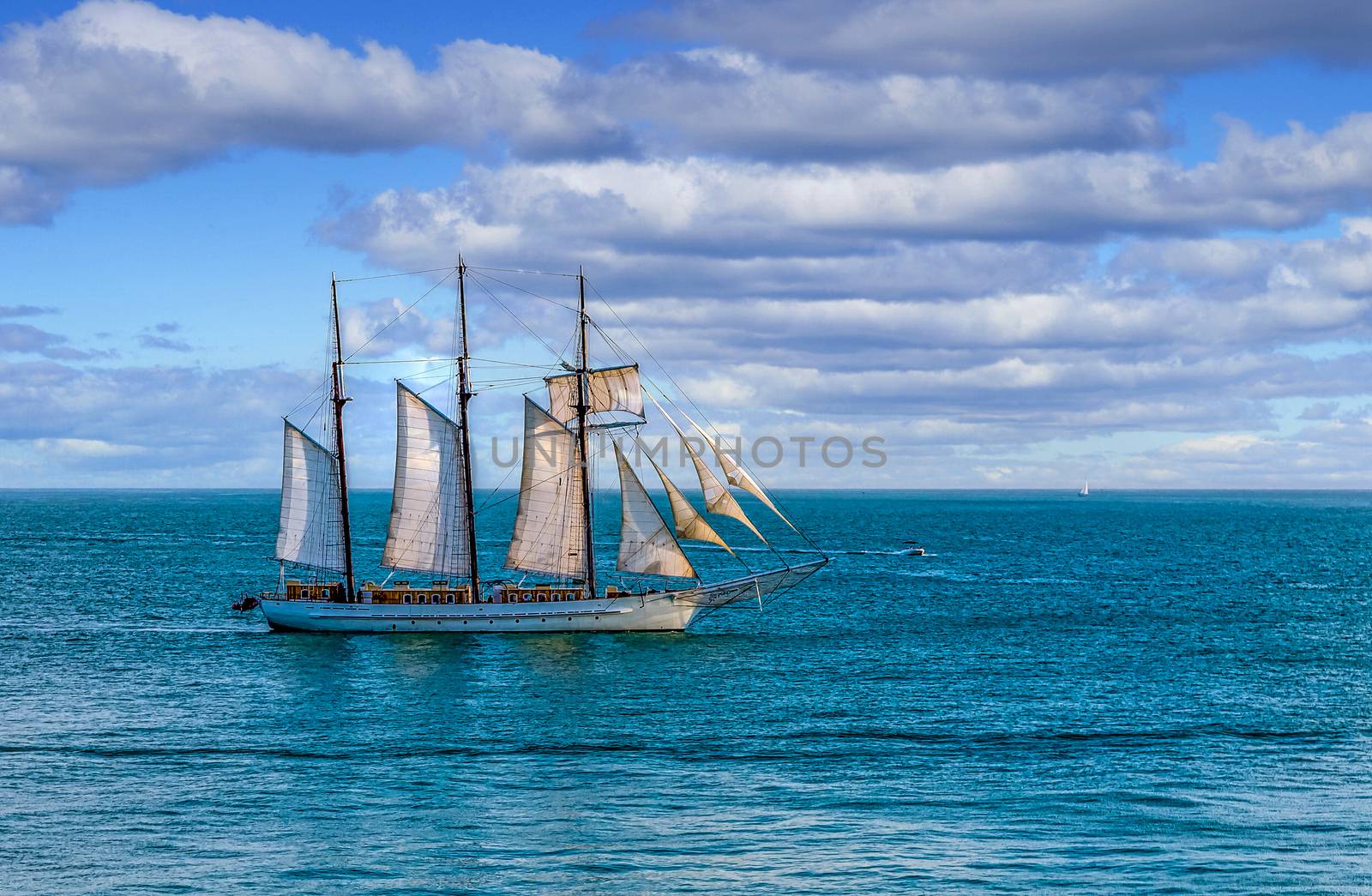 Schooner under sails sailing across a bay under beautiful skies