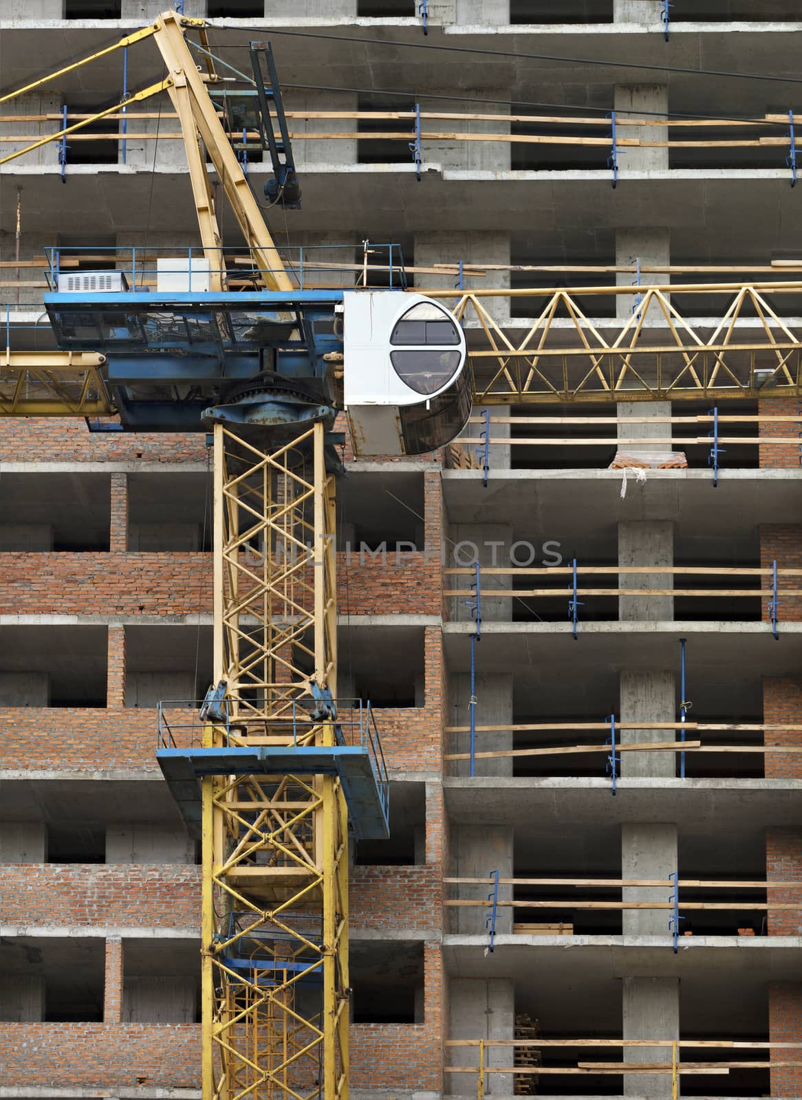 Fragment of facade a house under construction, modern building is under construction, tower building crane are directed upwards