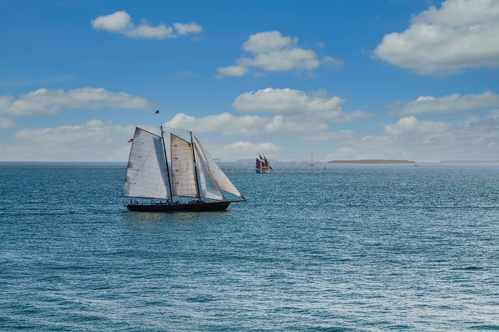 Schooner under sails sailing across a bay under beautiful skies