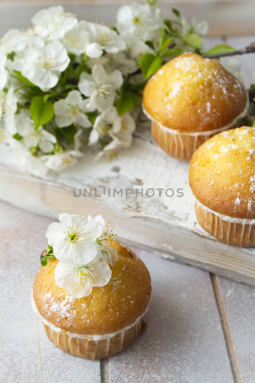 Mini muffins decorated with cherriy flowersc close up. Vertical image