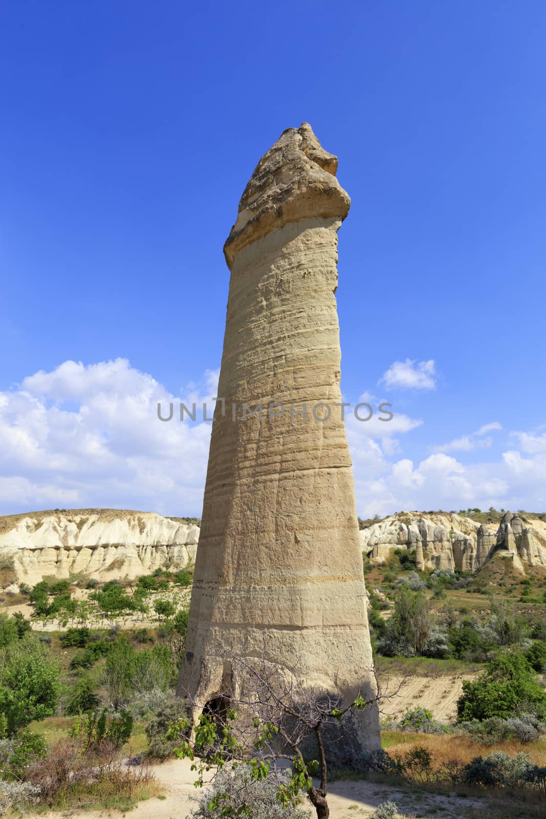 The powerful monument of the ancient rock soars its conical top in the valley of Cappadocia into the blue sky by Sergii