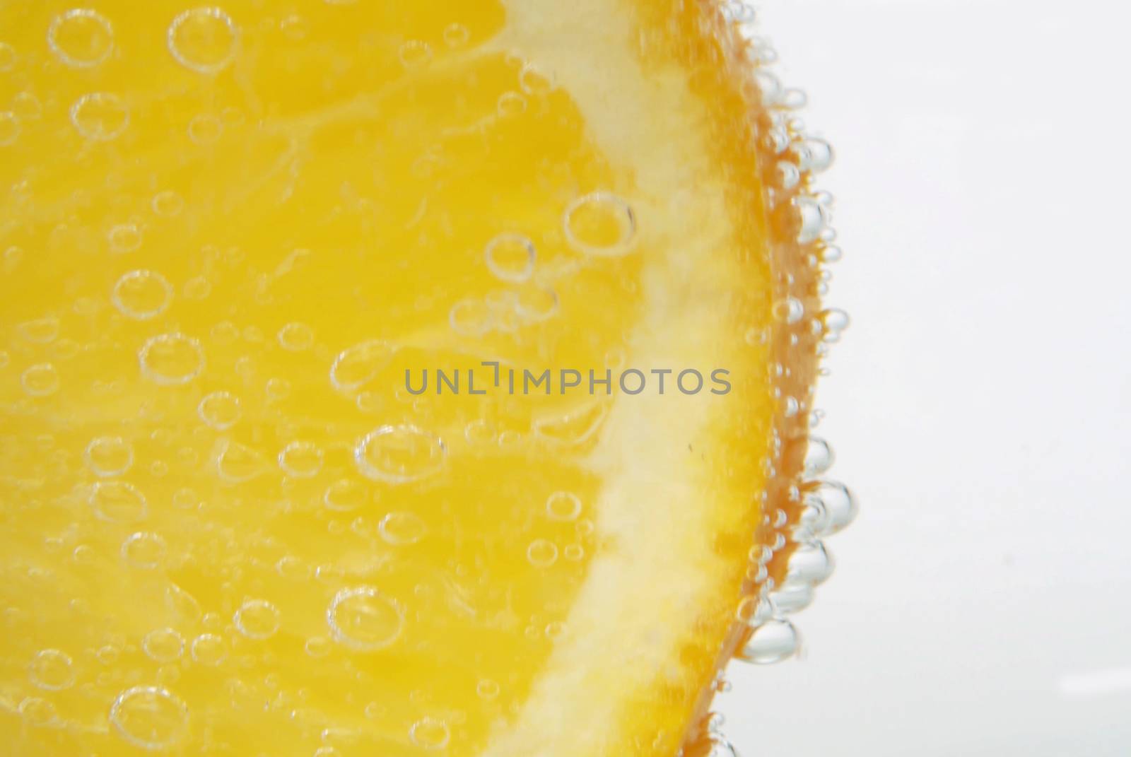 Macro shooting sliced orange in tonic, soda fizzy on a white background. Refreshing mineral water in a glass. Gas bubbles. Healthy drink