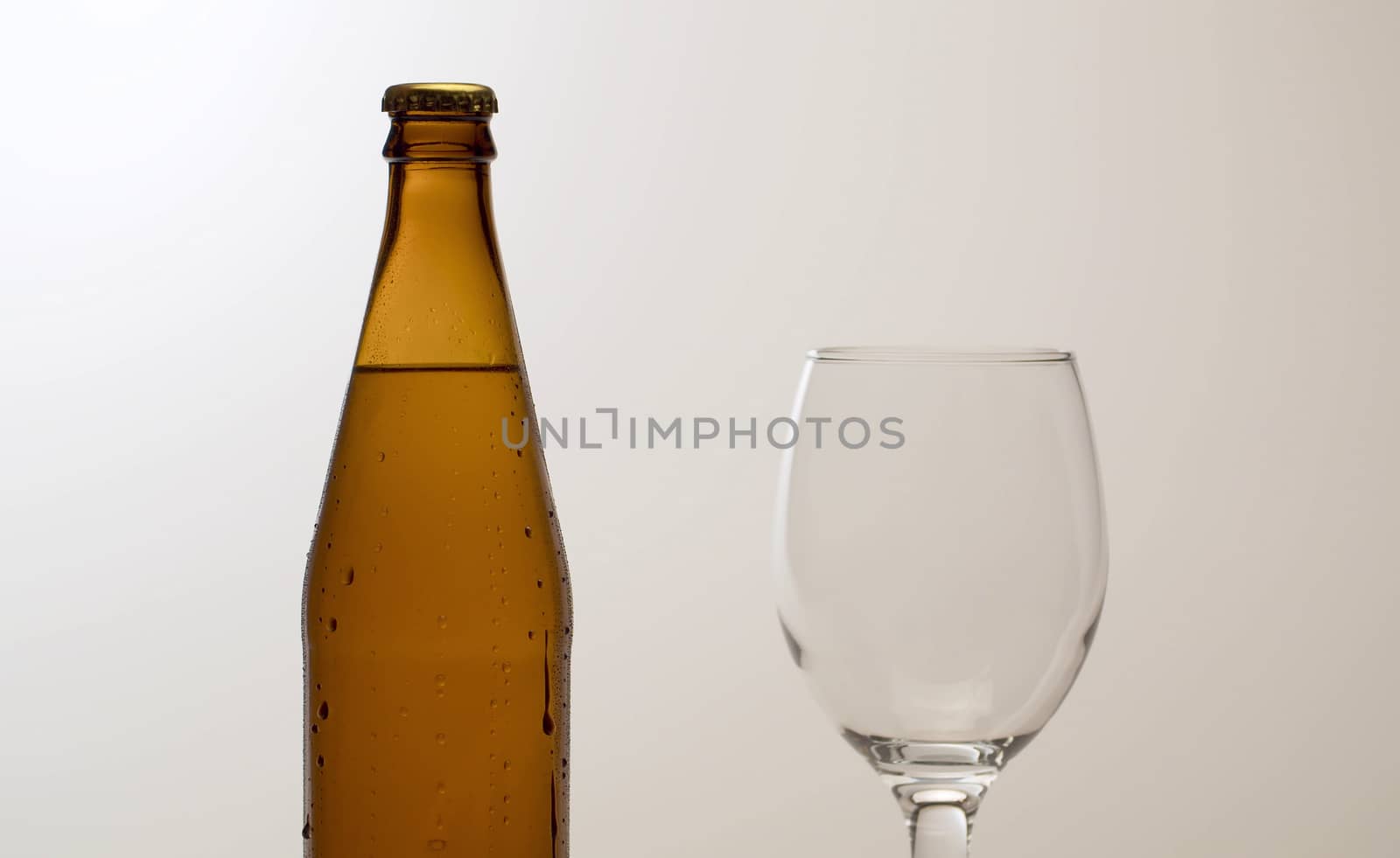 Close up misted bottle of cold beer on the table. White background. Drops of water flowing down. Craft beer closeup