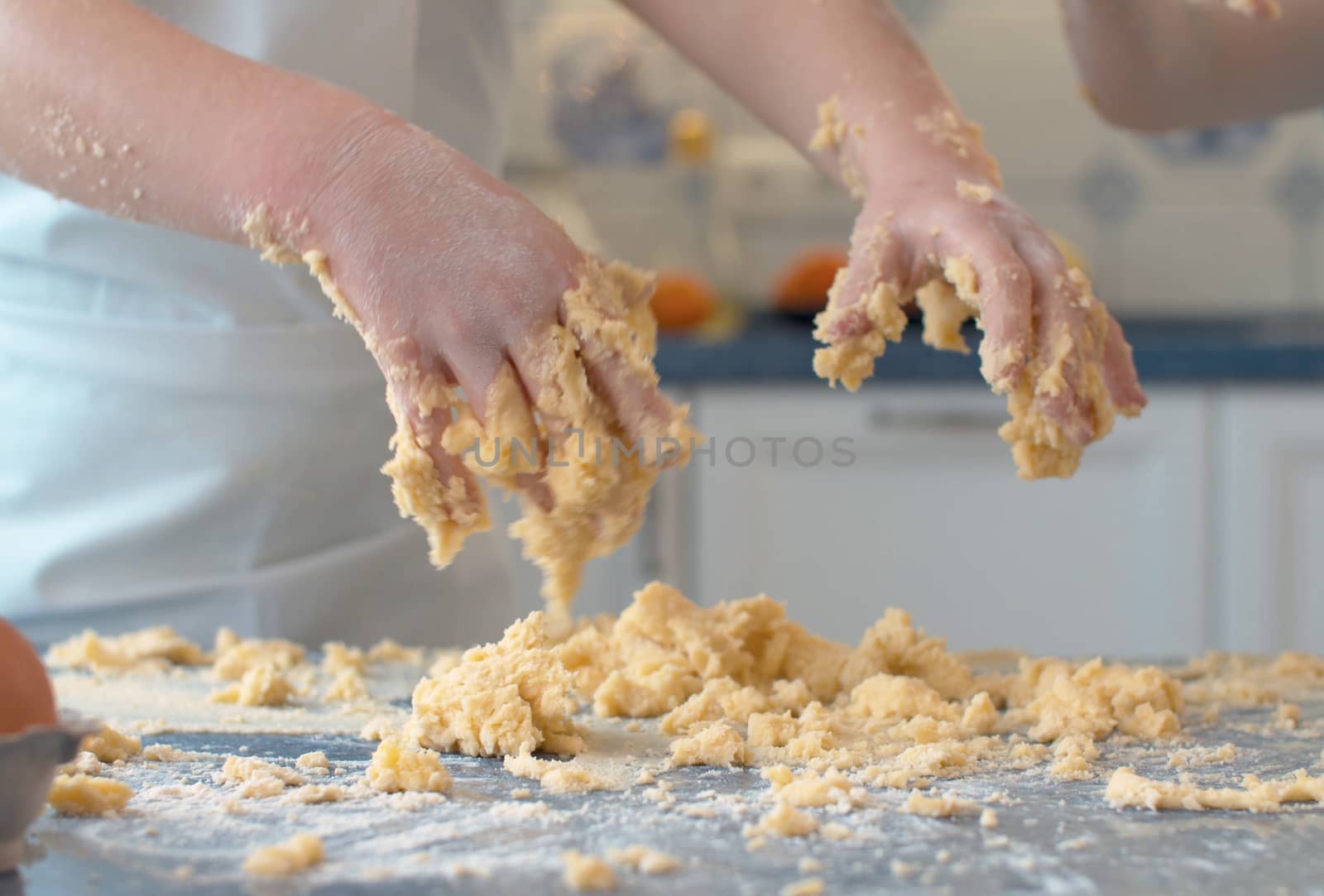 Close up child's hands in the dough. Kid cooking pastry in bright kitchen.