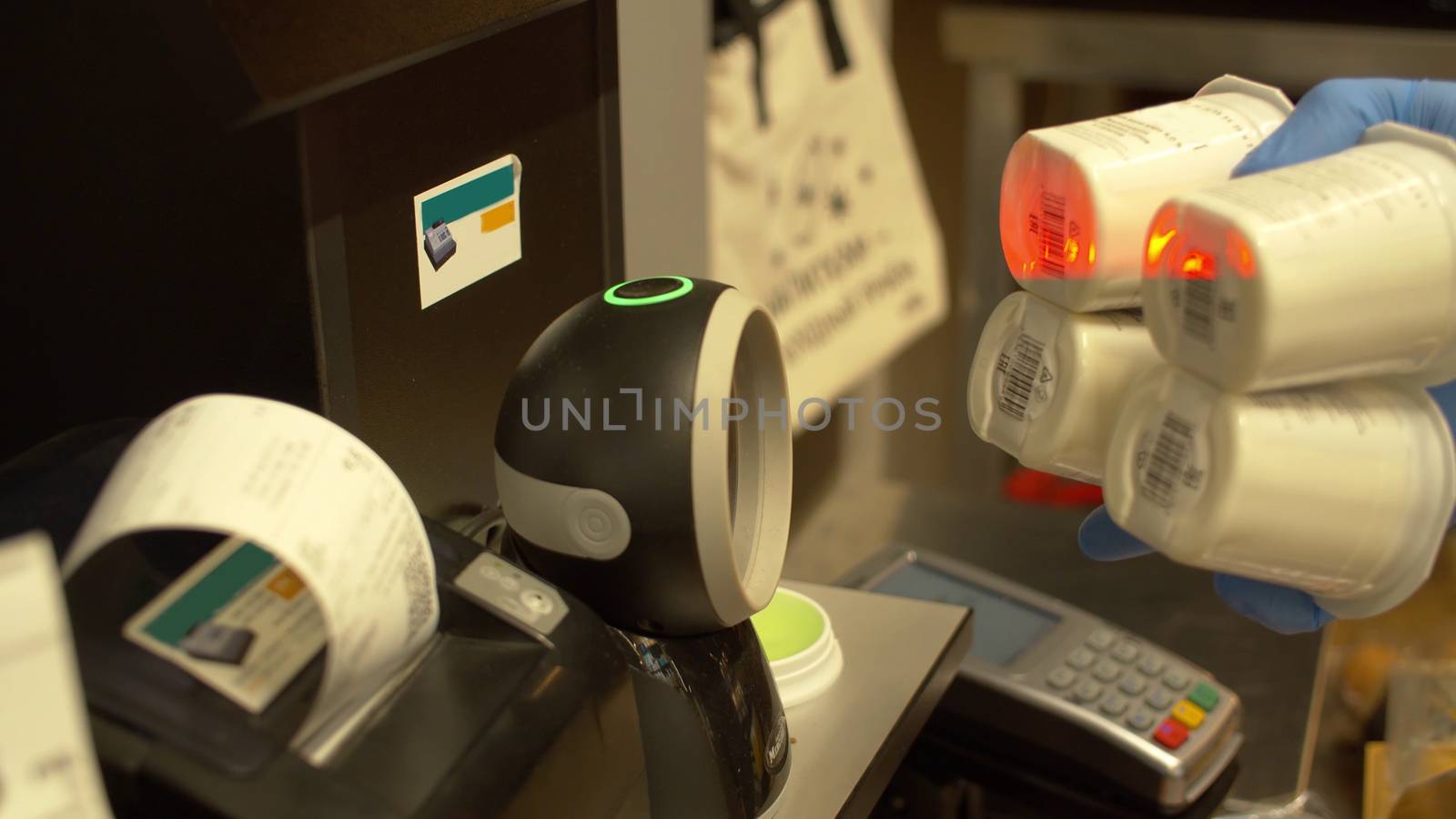 Close up hands in latex gloves scanning yogurt on a self-service scanner at supermarket and then on the monitor corrects the amount. Self-checkout counter in the store during coronavirus epidemic.