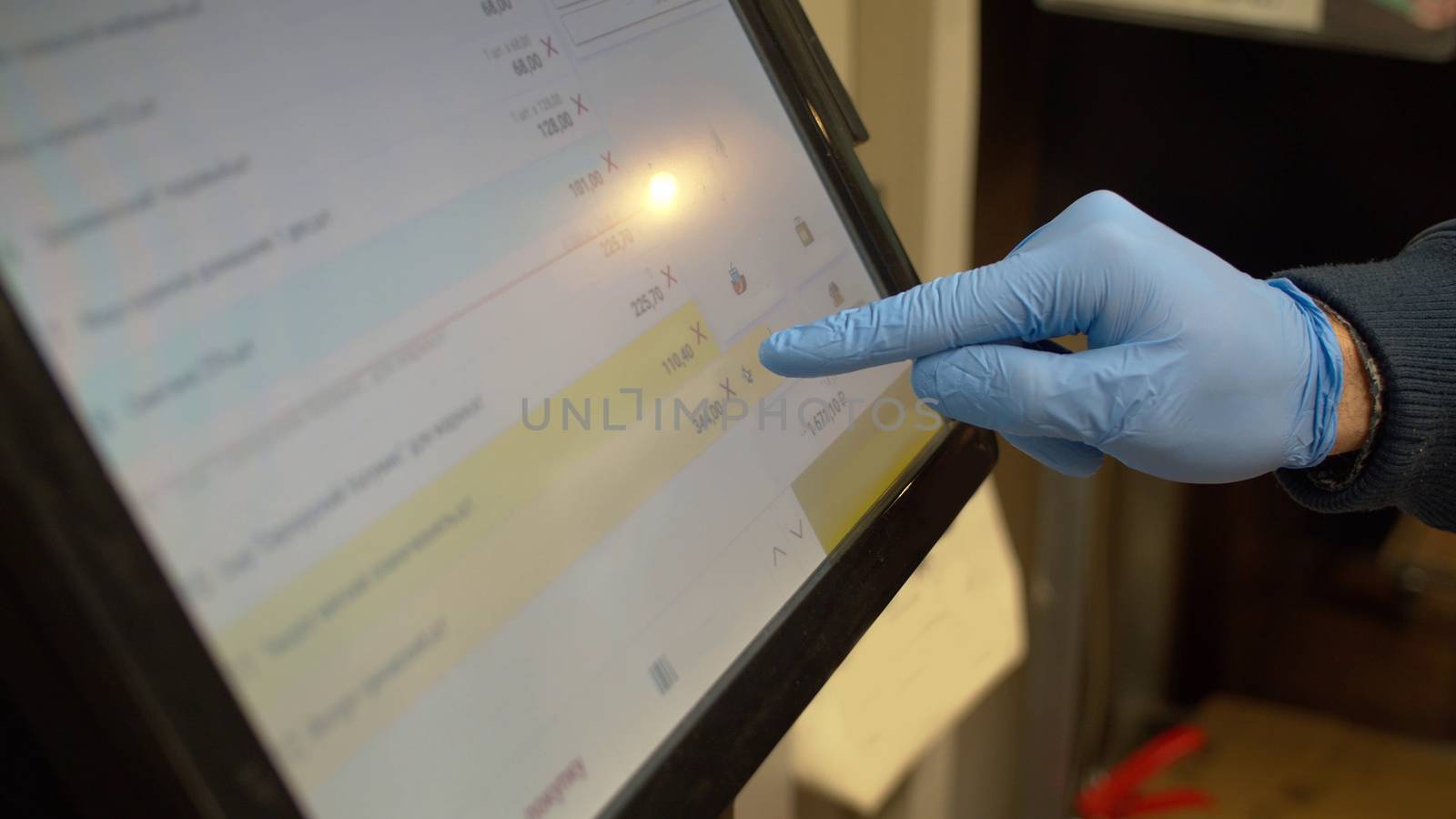 Close up hand in rubber gloves at supermarket typing on touch screen of self checkout. Coronavirus epidemic.