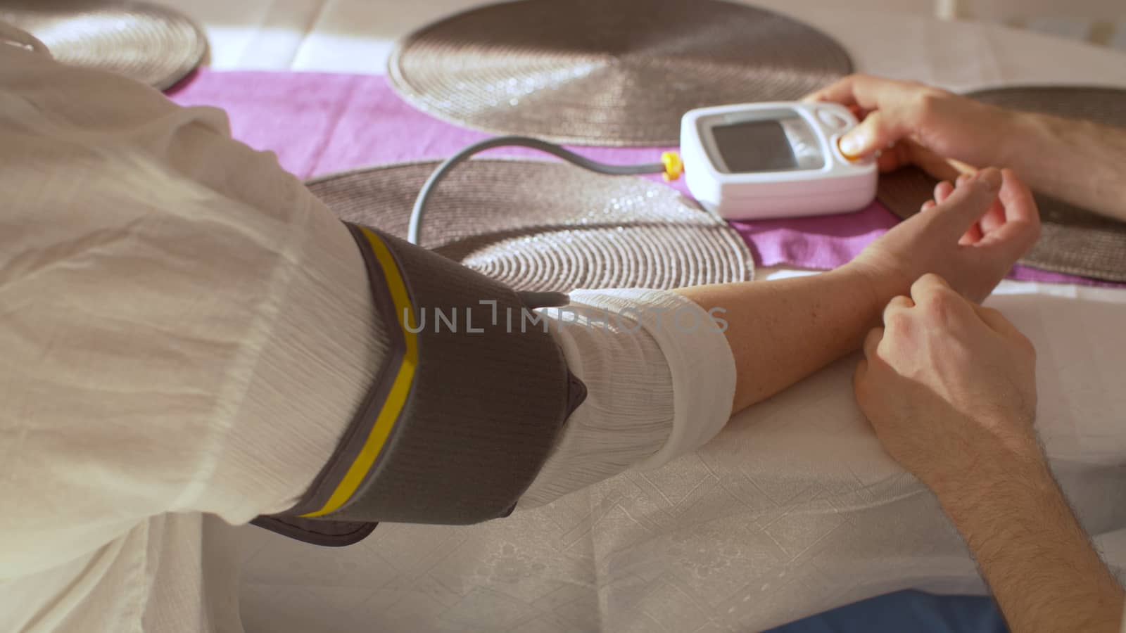 Close up hands of a young man to measuring blood pressure of senior mother at home. Healthcare concept
