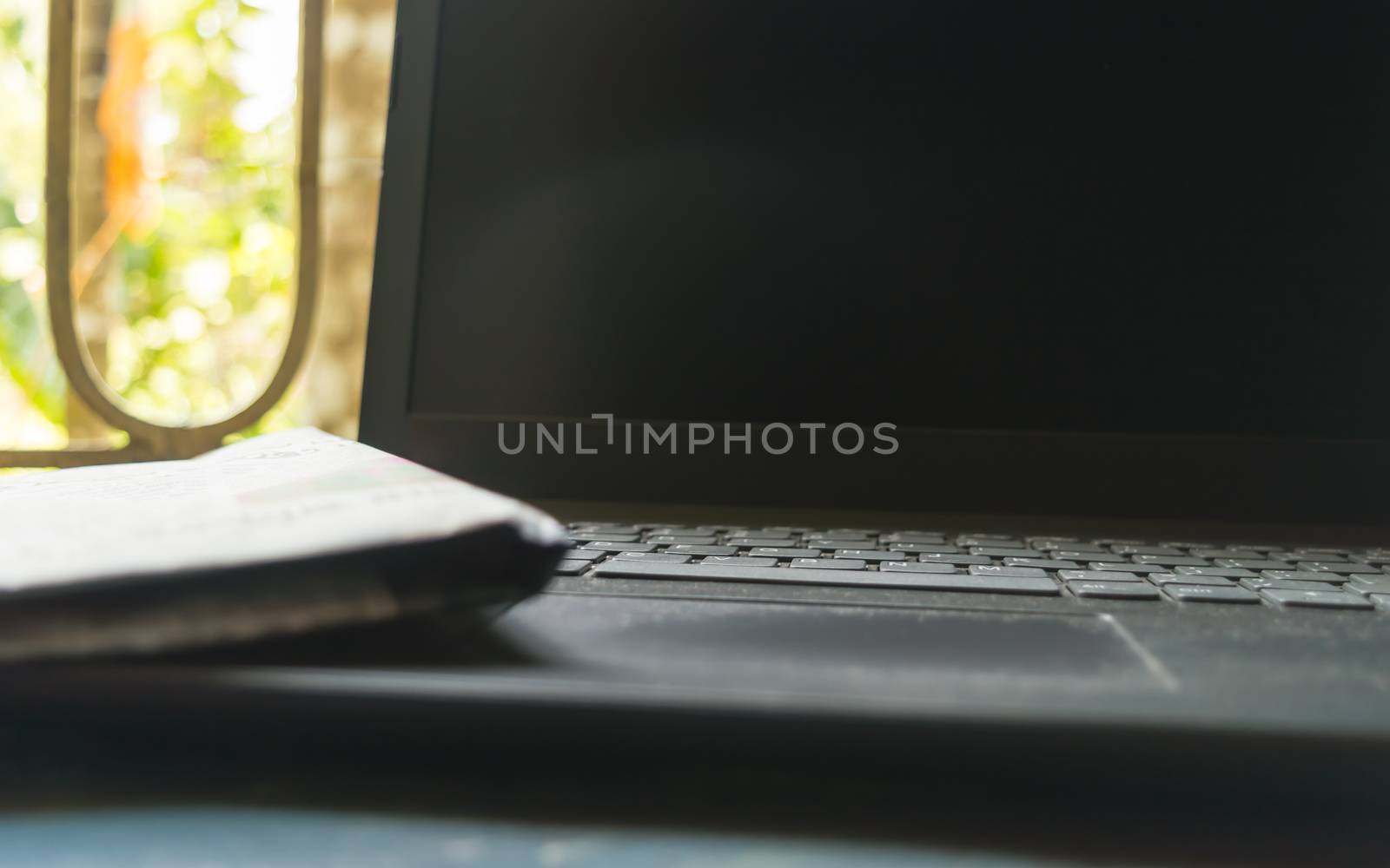 Close Up Newspaper placed on laptop keyboard. Morning sunlight coming from window. Media Information medium and wireless technology background concept. Selective focus. Shallow depth of field.