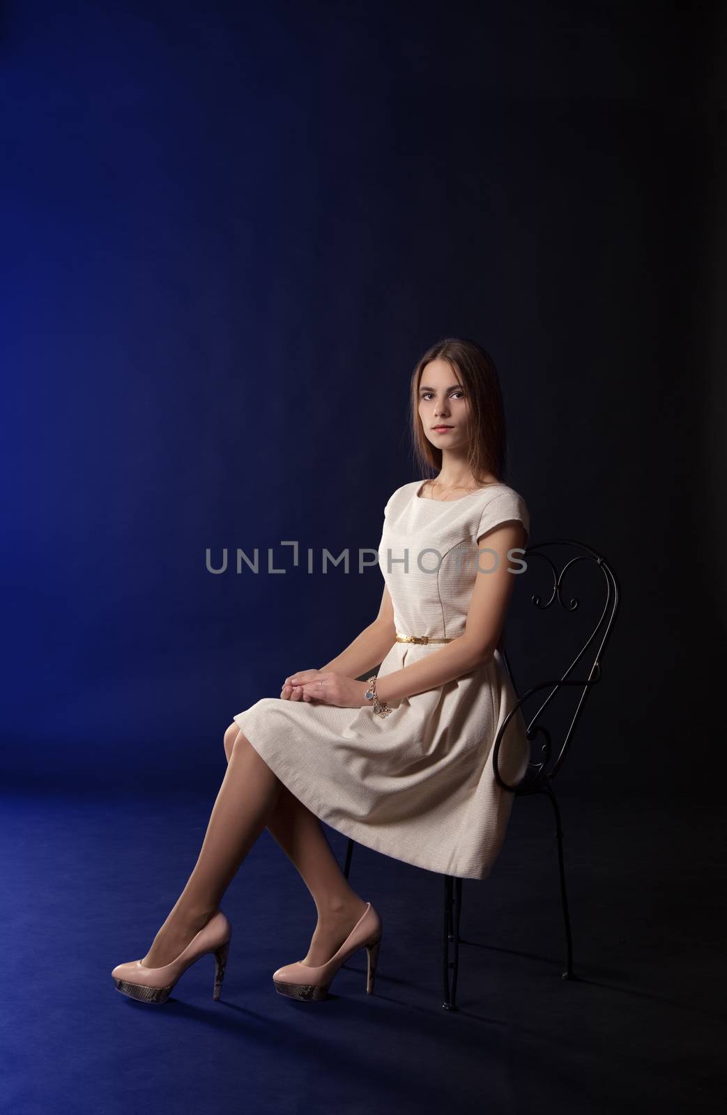 young beautiful girl in light dress sitting on a chair