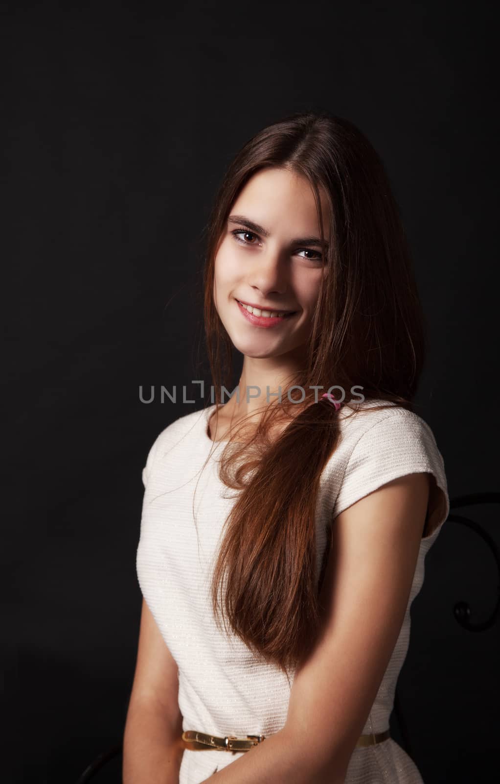 portrait of a beautiful young smiling girl in a bright dress on a black background