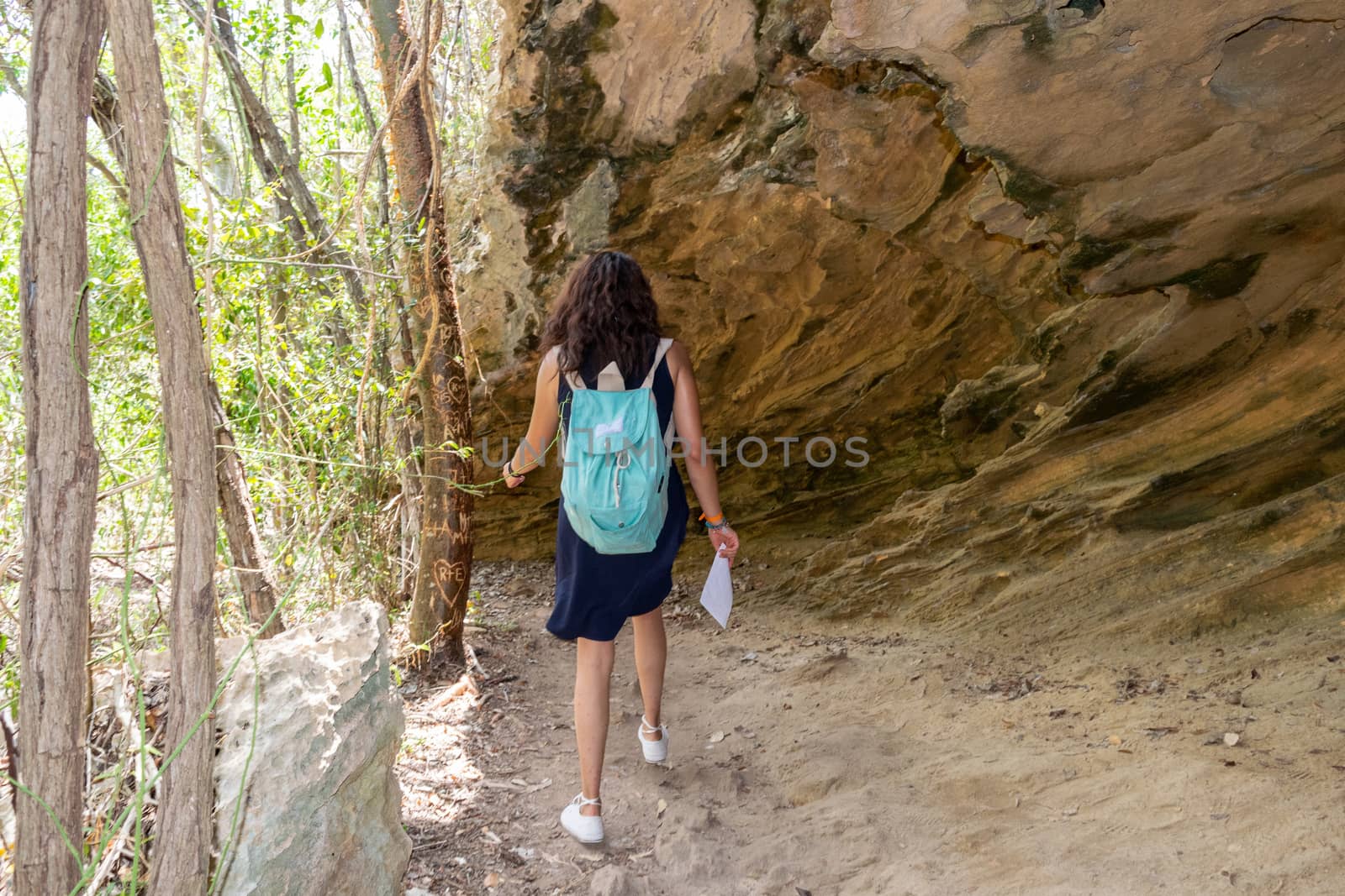 Woman walking under a big rock by Tonhio