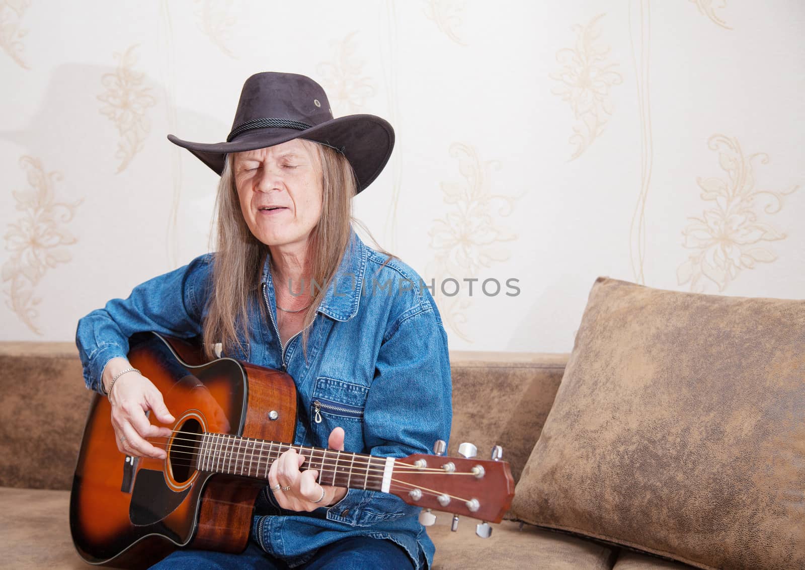 middle-aged man in a hat plays guitar and sings by raddnatt