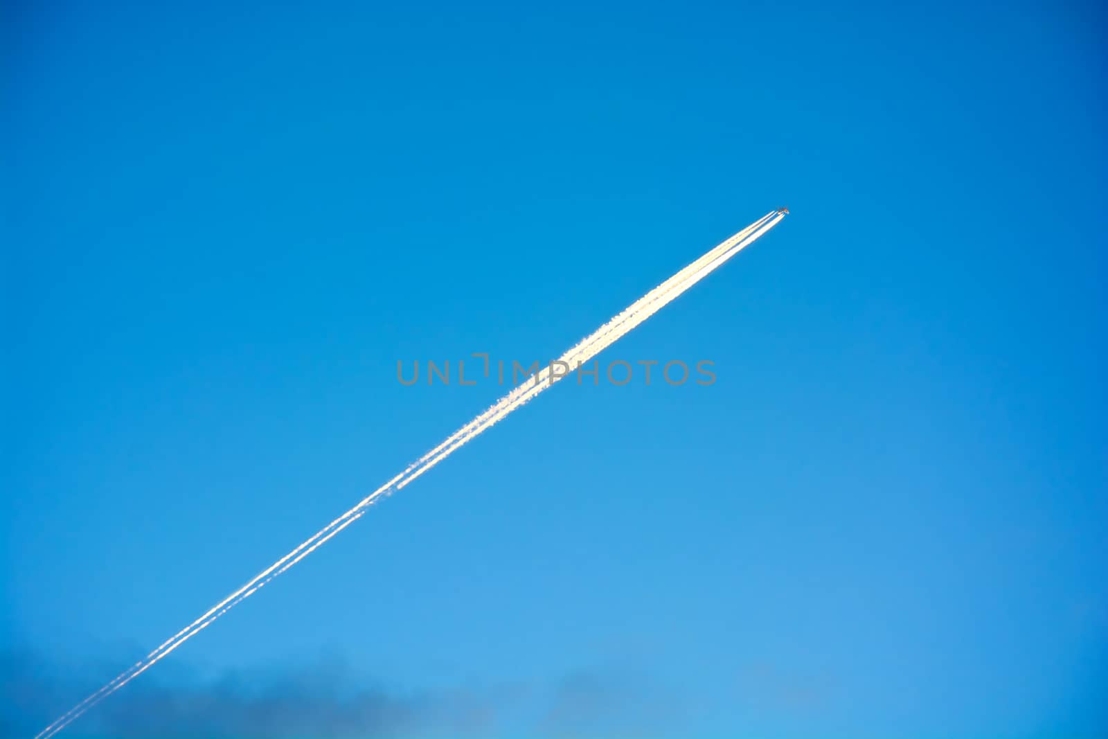 Plane and plane trails on the blue clean sky.