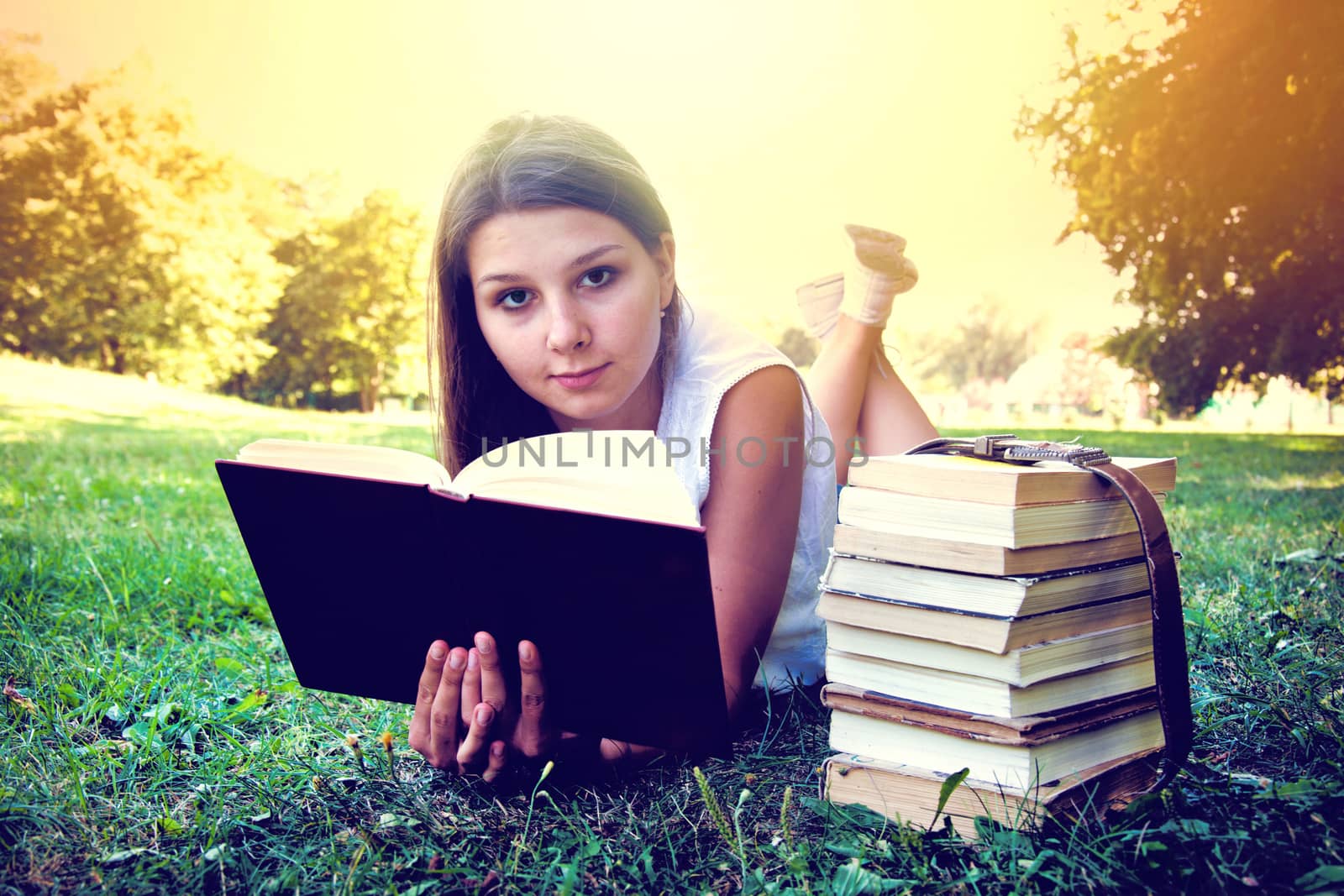 Student girl reading a book on campus grass. Education conceptual image. Instagram vintage picture.