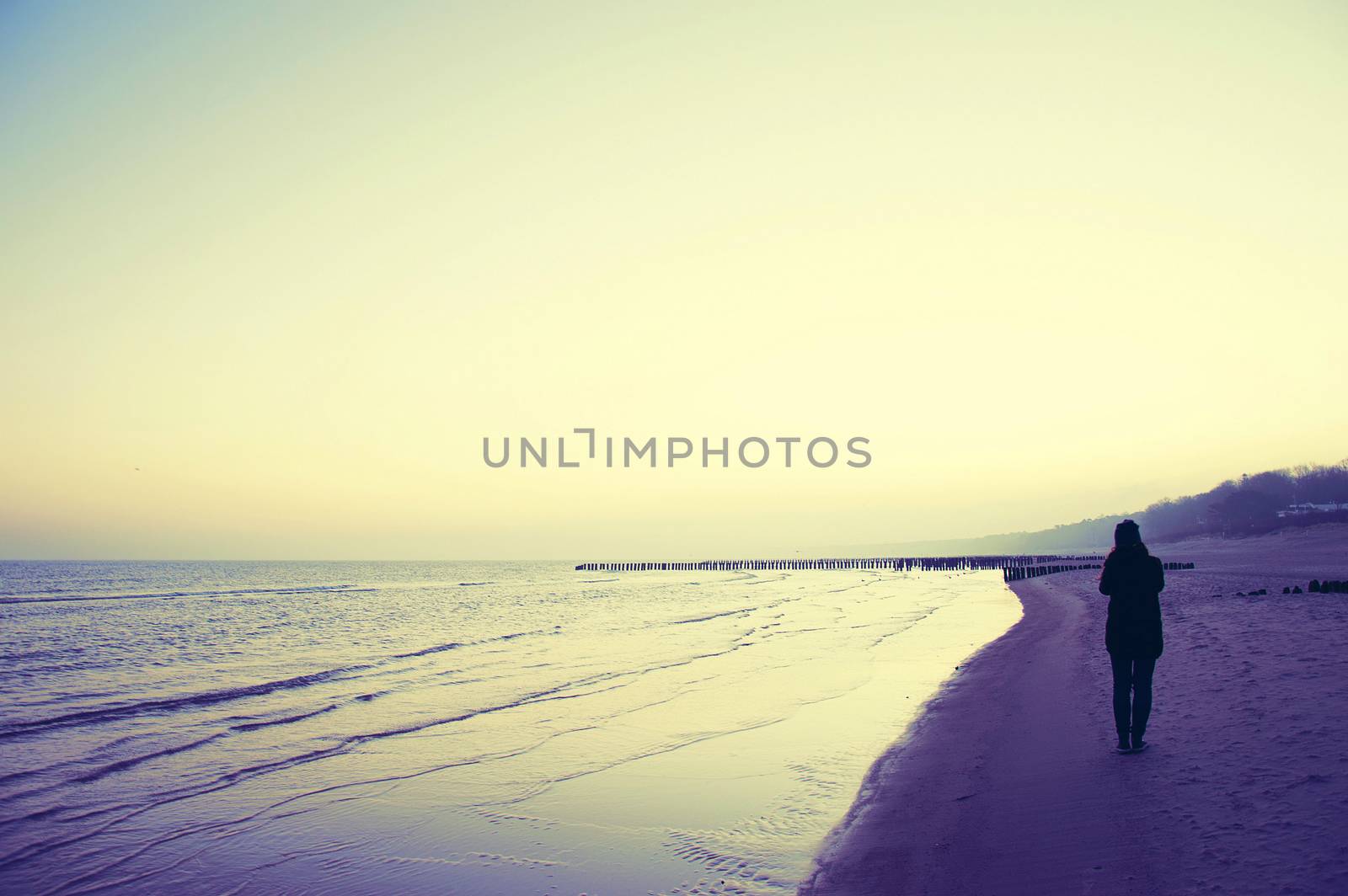 Emotion conceptual image. Lonely woman walking on the beach. Instagram vintage picture.