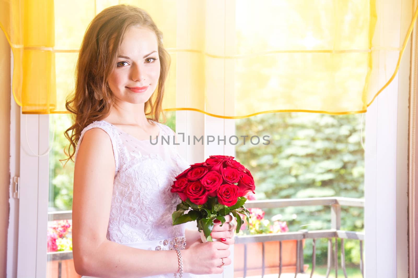 Young beautiful bride in wedding dress with red rose bouquet. Marriage and wedding concept image.