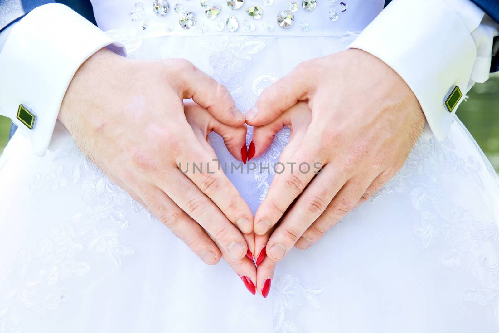 Bride and groom hold hands in love heart shape. Marriage and wedding concept image.