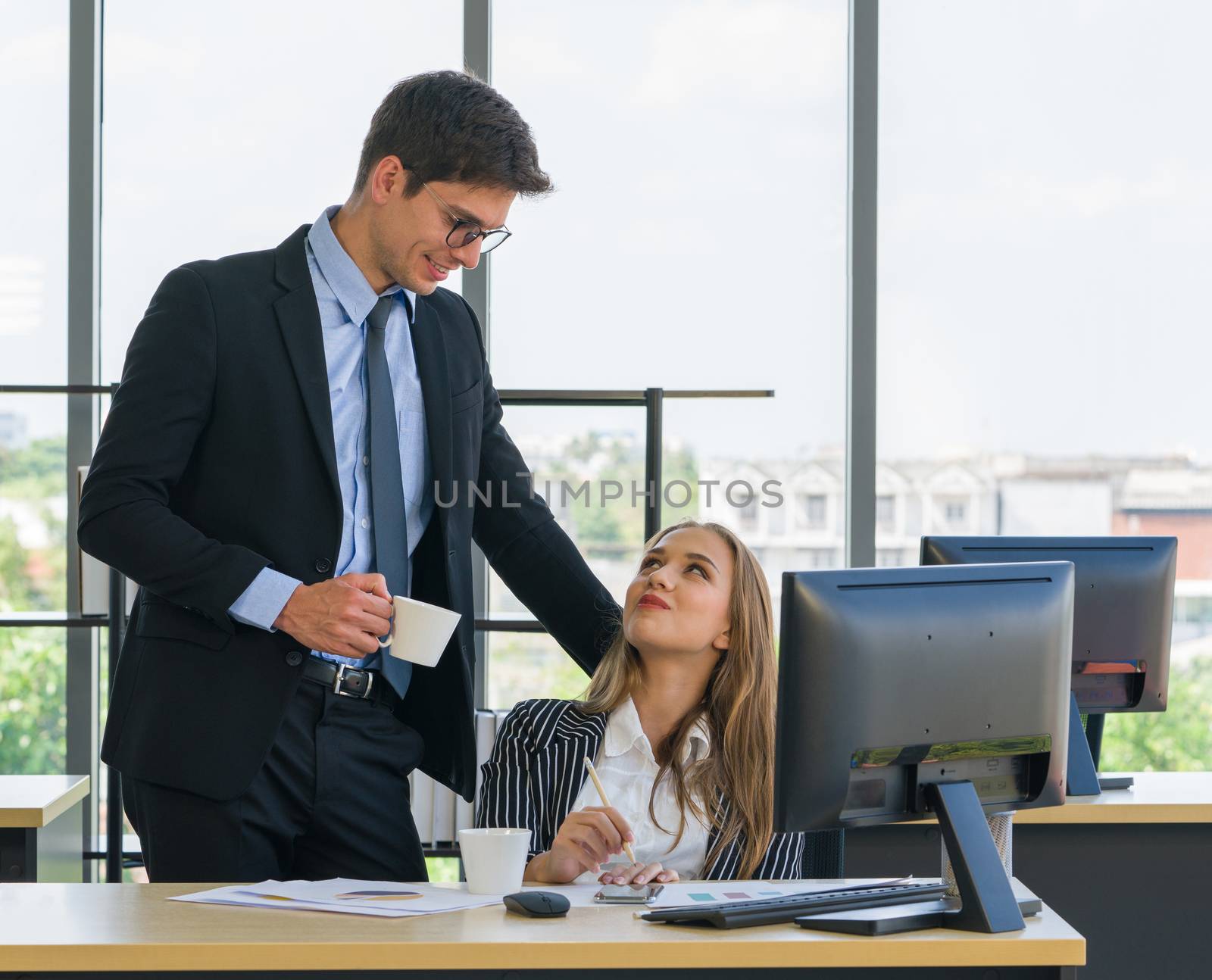 Young couples spend coffee breaks together in the modern office. Both made eye contact and smiled at each other after agreeing on where to go after work.