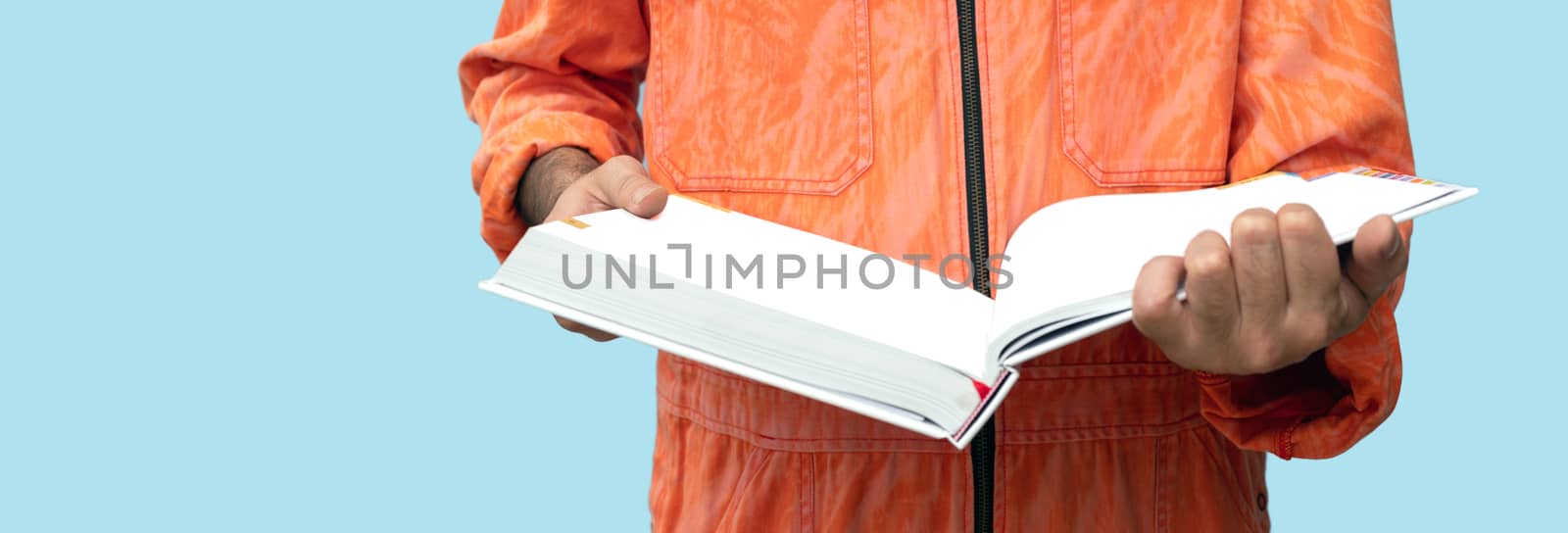A thick hardcover book in the hands of a chief mechanic wearing an orange uniform dress. Portrait with studio light.