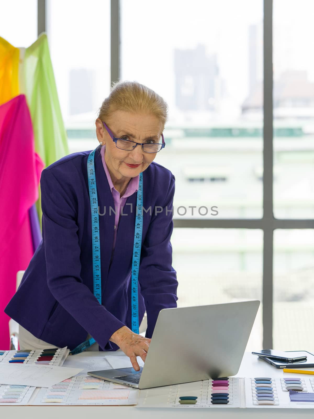 A senior designer uses her laptop computer to research information for modern design. by chadchai_k