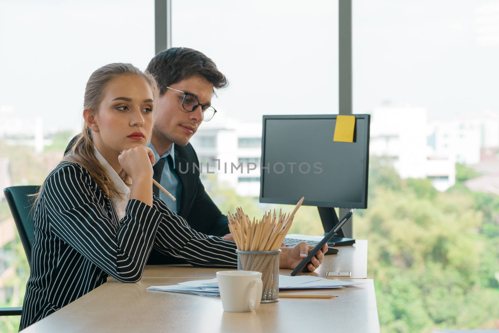 Teenager employees made a disgruntled expression of colleagues after the meeting. The man in the suit sat vacant at his desk. Morning work atmosphere In a modern office.