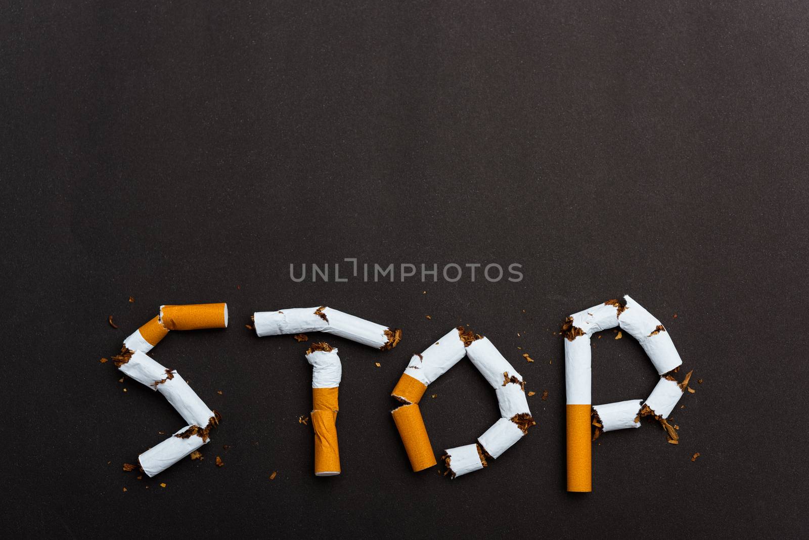 31 May of World No Tobacco Day, no smoking close up word STOP spelled text of the pile cigarette or tobacco on black background with copy space, and Warning lung health concept