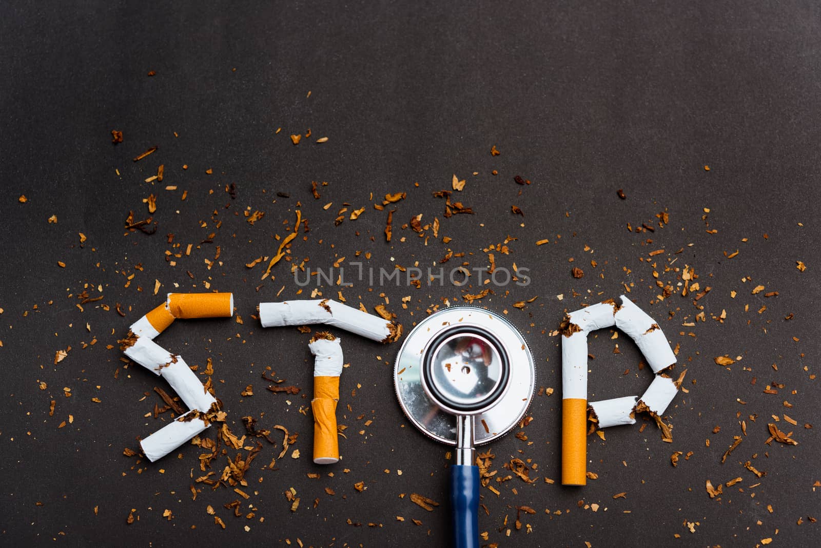 31 May of World No Tobacco Day, no smoking close up word STOP spelled text of the pile cigarette or tobacco and doctor stethoscope on black background with copy space, and Warning lung health concept