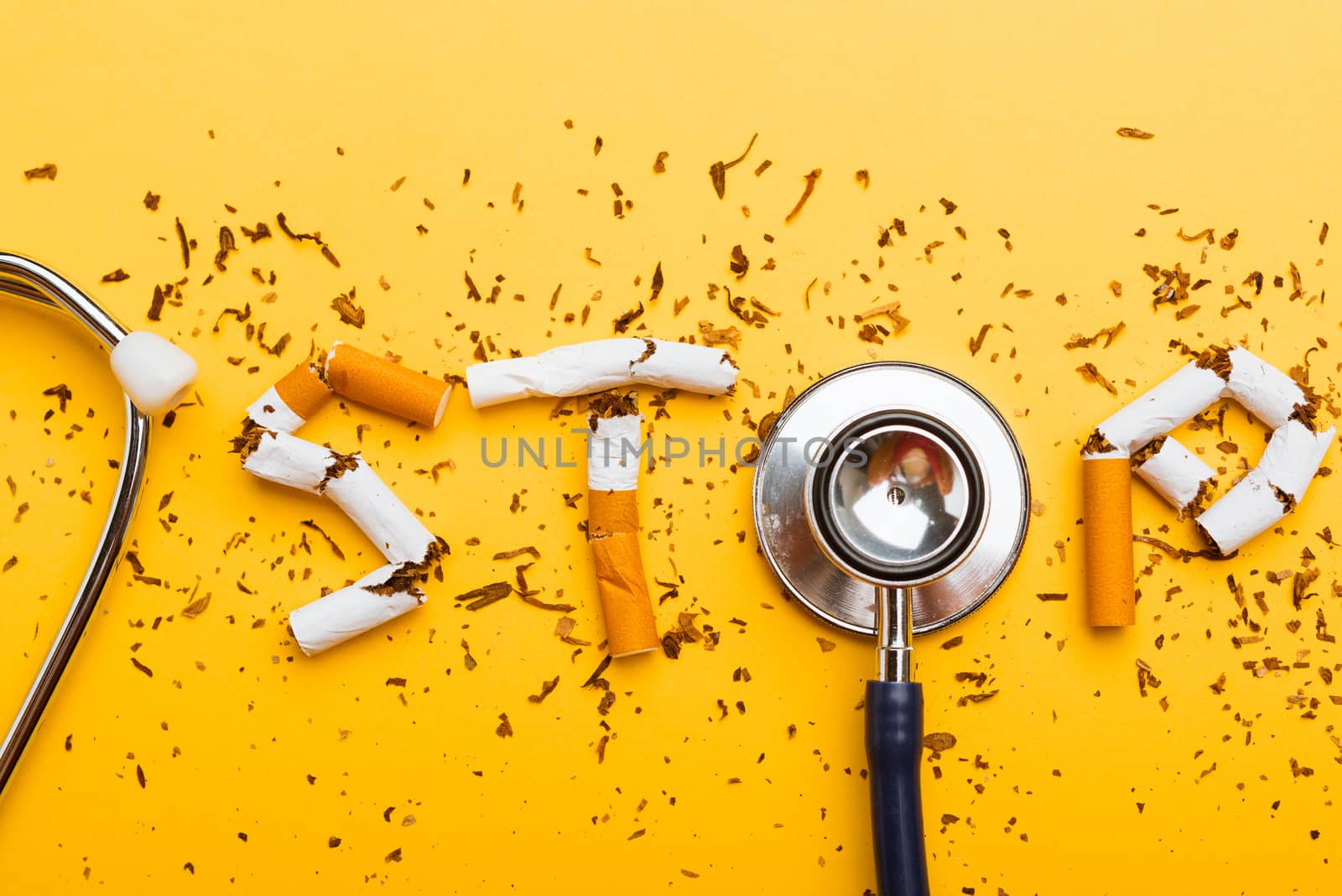 31 May of World No Tobacco Day, no smoking close up word STOP spelled text of the pile cigarette or tobacco and doctor stethoscope on yellow background with copy space, and Warning lung health concept