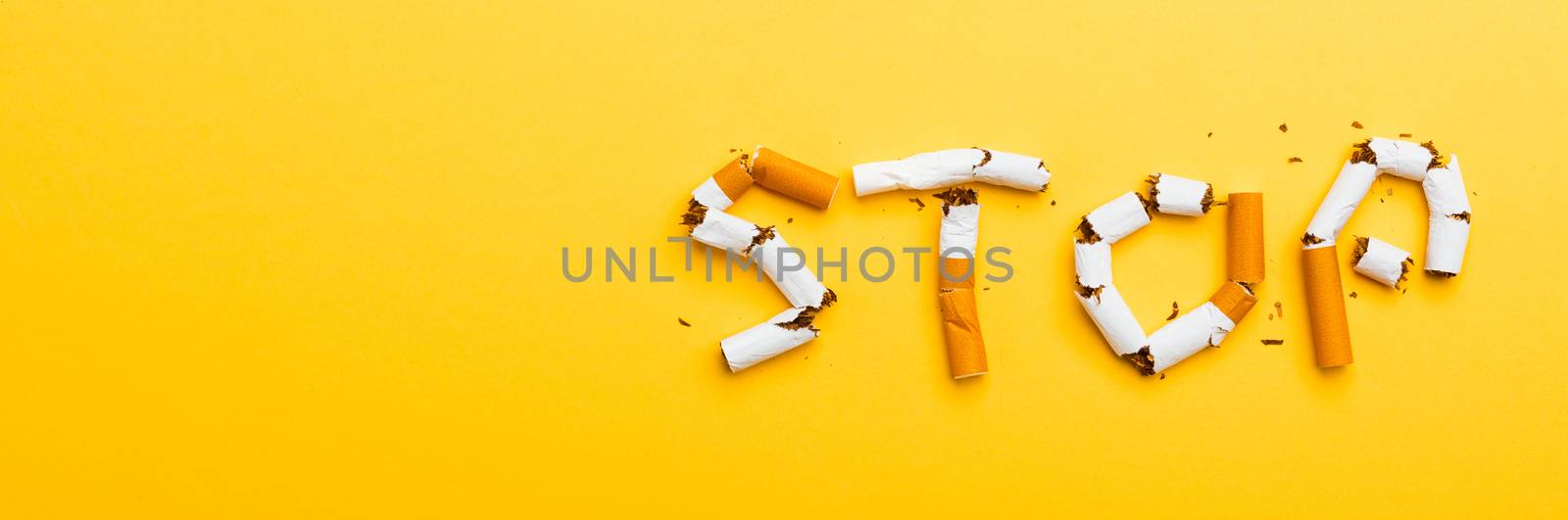 31 May of World No Tobacco Day, no smoking close up word STOP spelled text of the pile cigarette or tobacco on yellow background with banner copy space, and Warning lung health concept