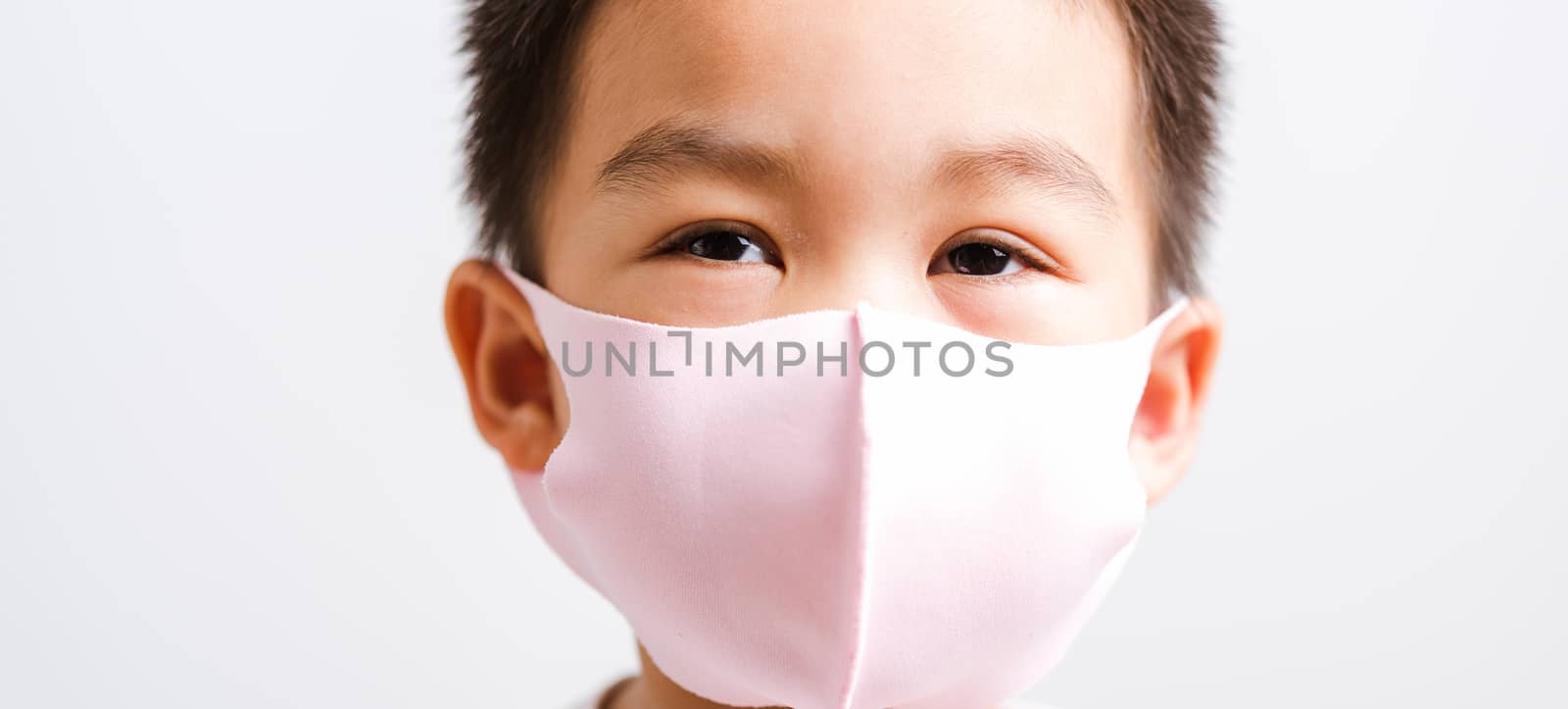 Portrait Asian little child boy wearing cloth face mask protective filter dust pm2.5, COVID-19 or coronavirus concept he looking to camera, studio shot isolated on white background with copy space