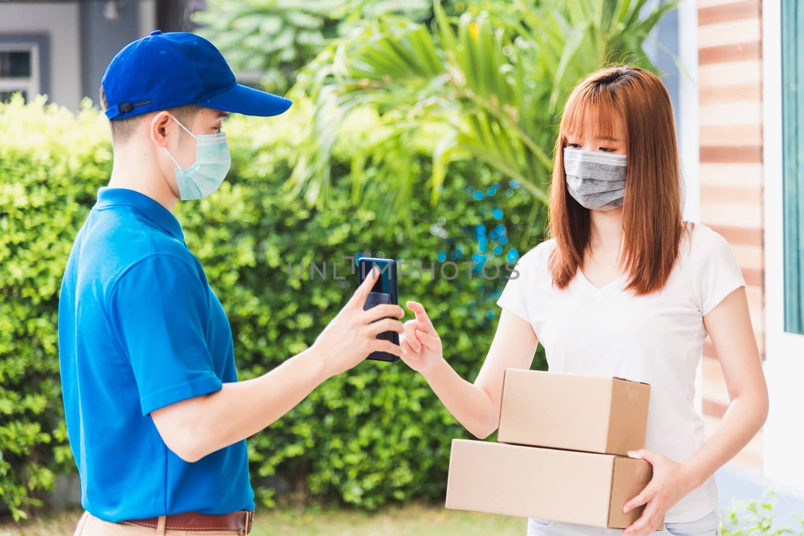 delivery express courier young man giving parcel boxes to woman  by Sorapop