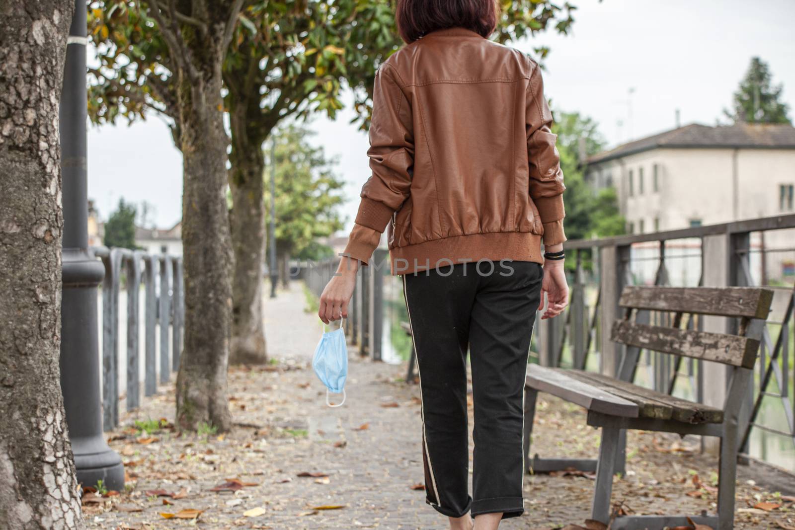 Detail of a girl's hand holding a medical mask while walking on the street 3 by pippocarlot