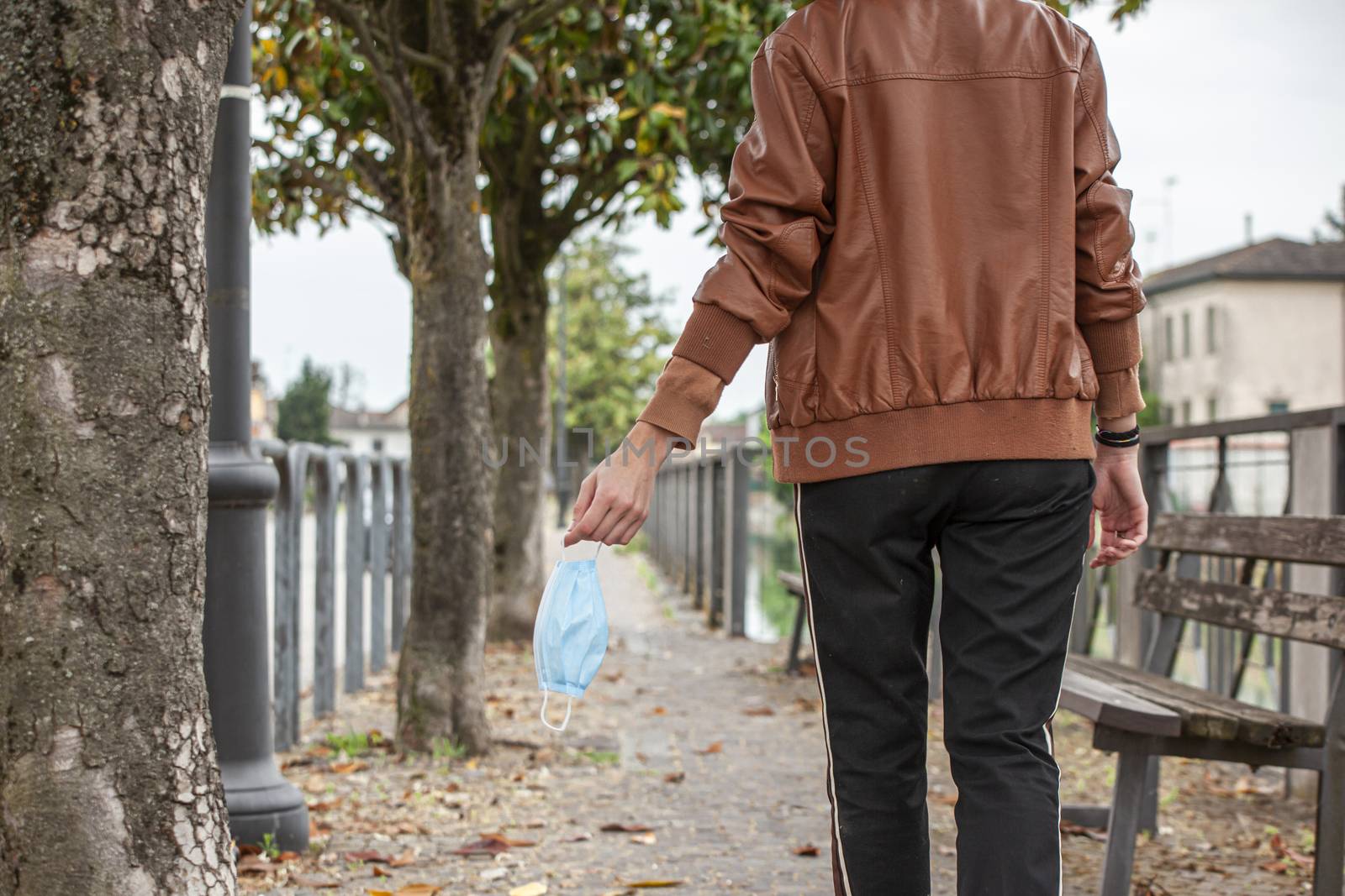 Detail of a girl's hand holding a medical mask while walking on the street during covid quarantine