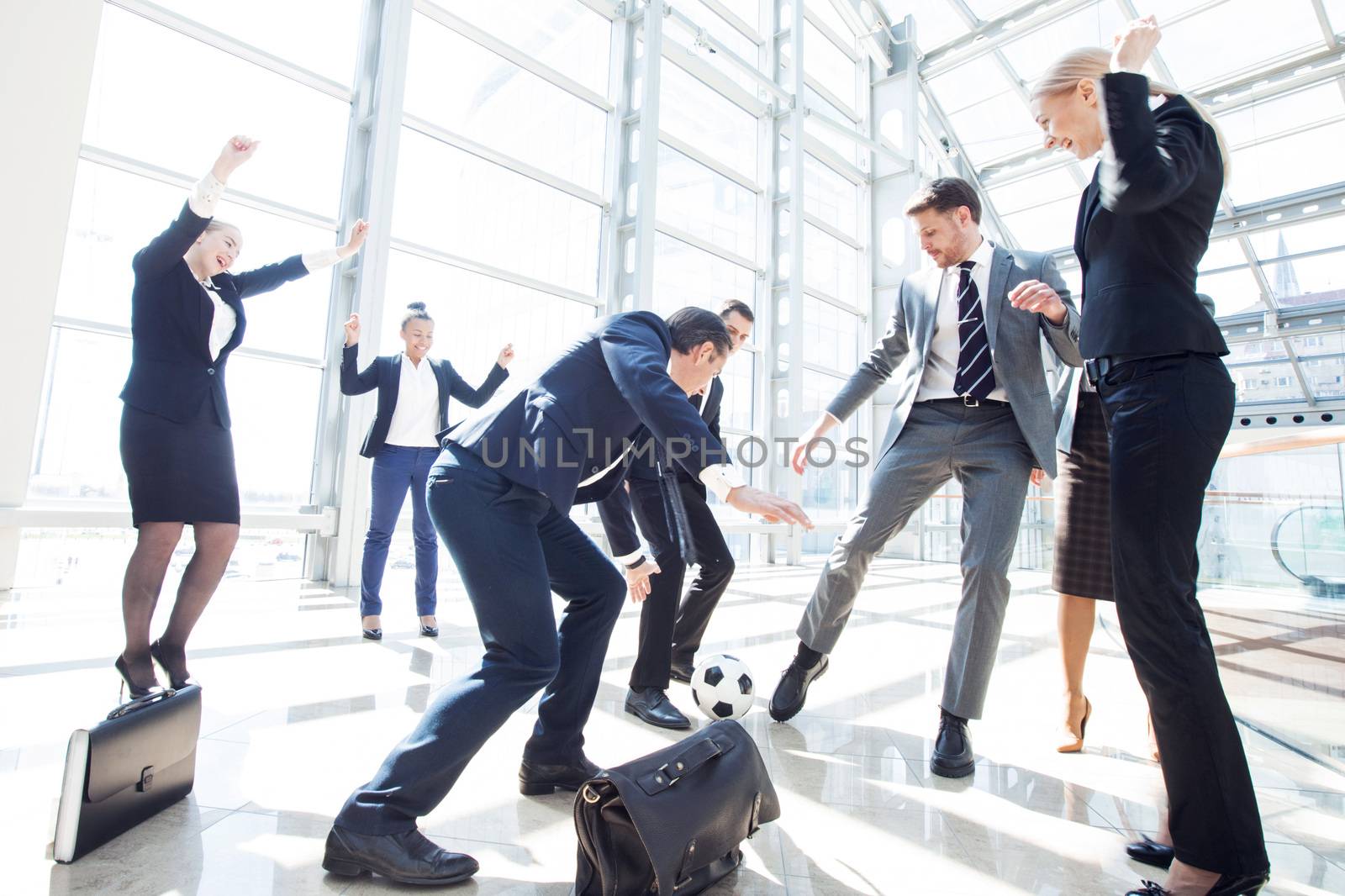 Business people team playing soccer having fun in office