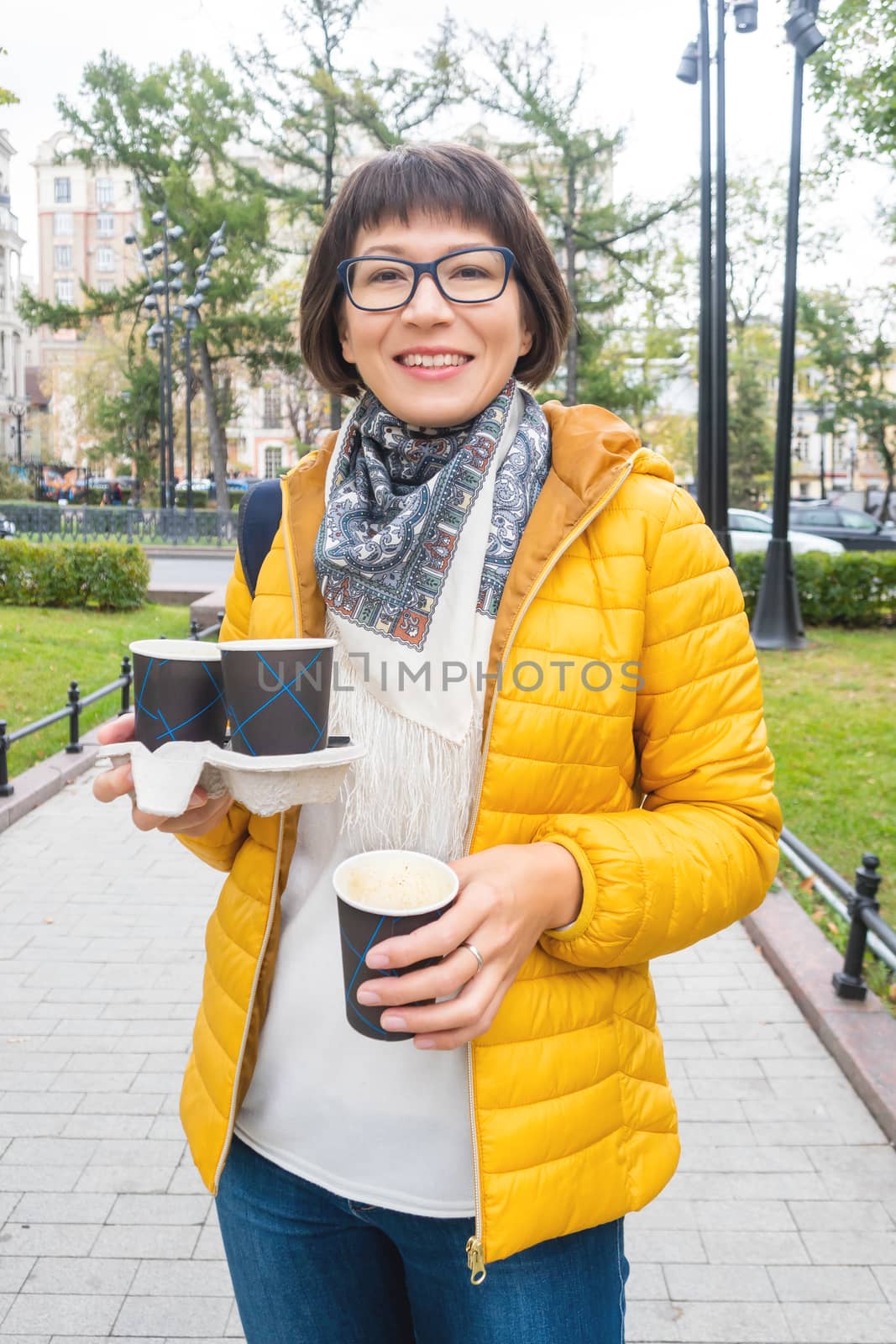 Take away coffee. Happy wide smiling women in bright yellow jack by aksenovko