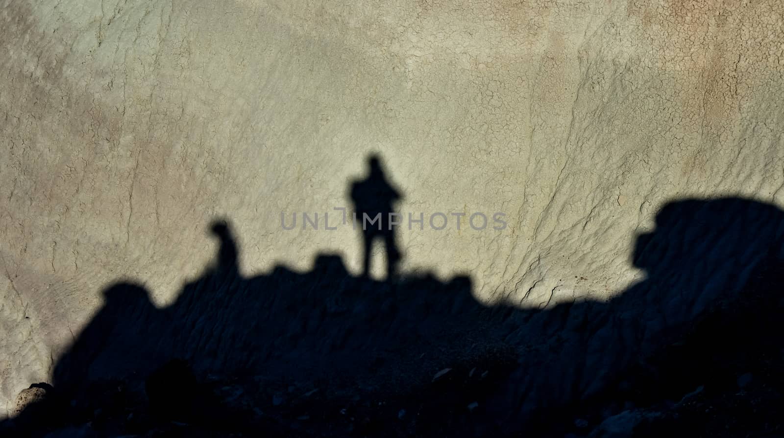 Shadow of a man against a background of dry cracked clay, cracks on the ground.