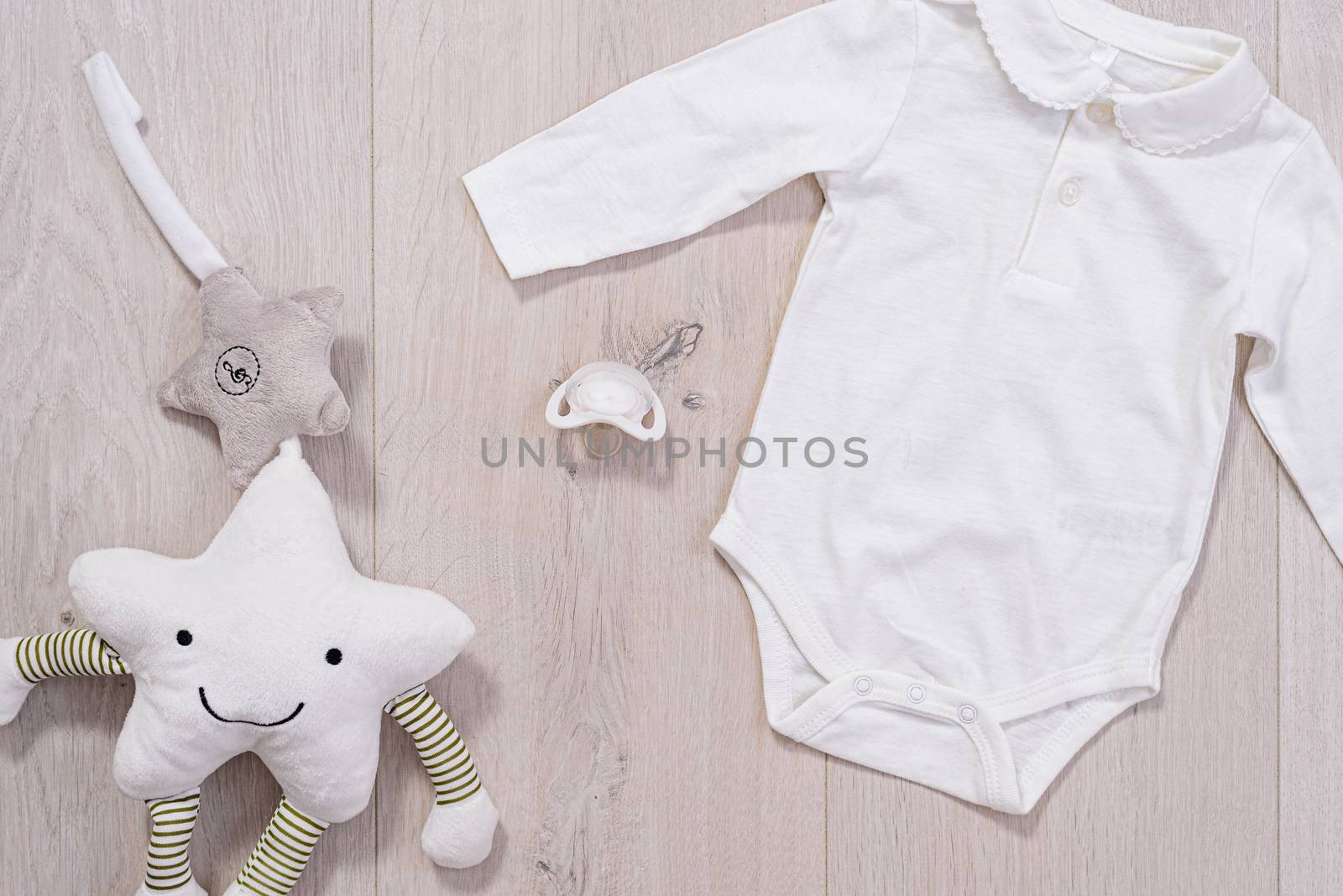 baby clothes concept. white suit for boy and girl and a baby pacifier on wooden background by jcdiazhidalgo