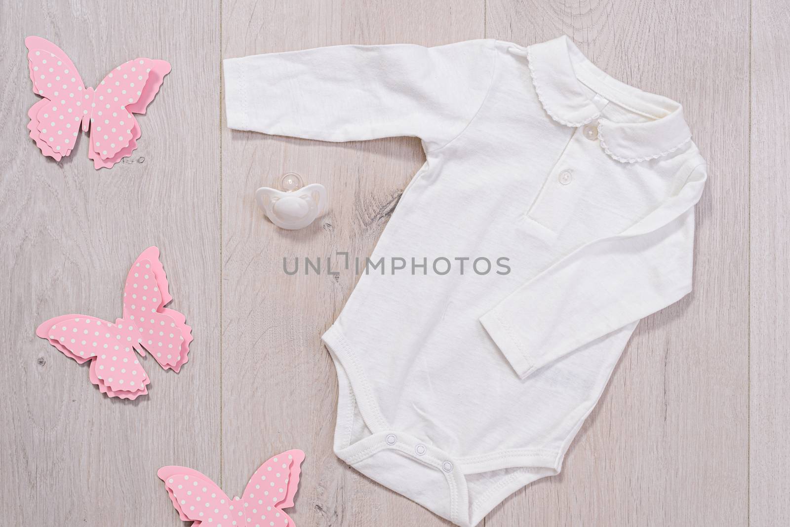 baby clothes concept. white outfit for girl on wooden background