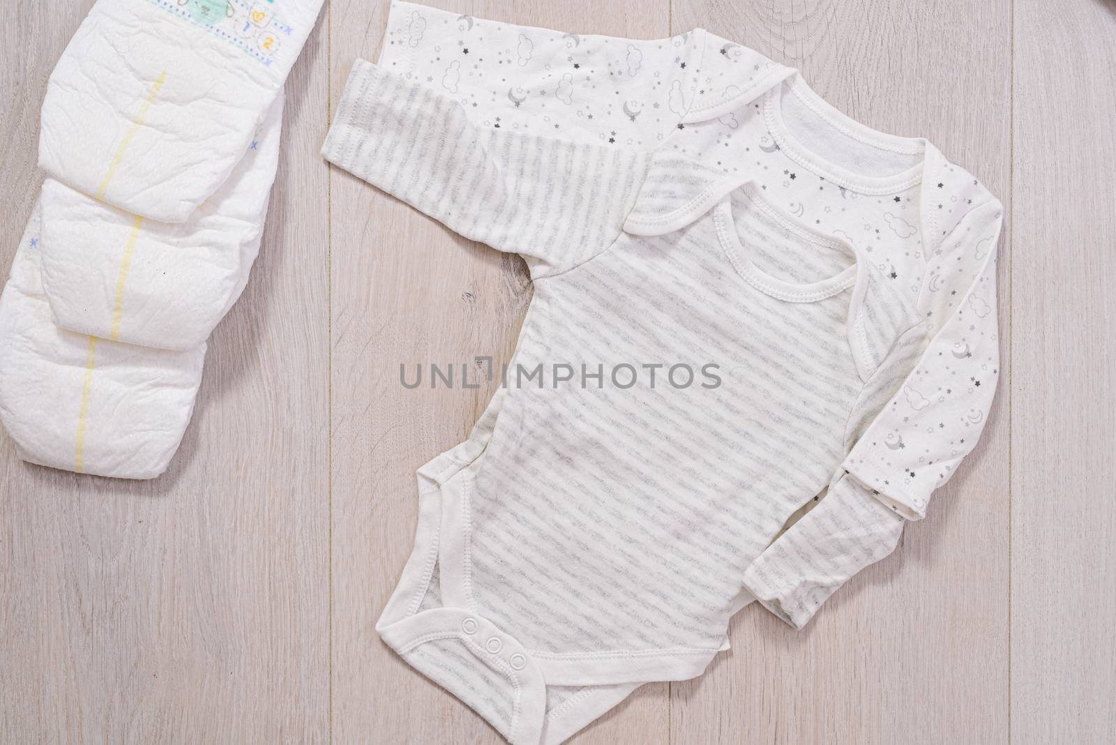 white baby clothes and diapers on wooden background. newborn by jcdiazhidalgo