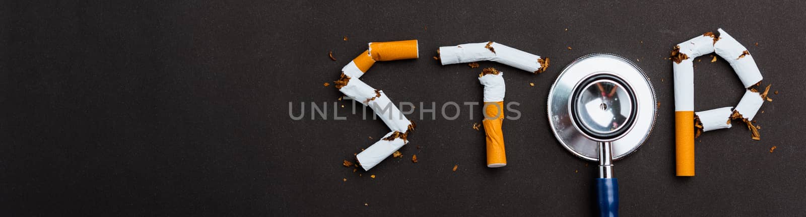 31 May of World No Tobacco Day, no smoking close up word STOP spelled text of pile cigarette or tobacco and doctor stethoscope on black background with banner copy space, Warning lung health concept