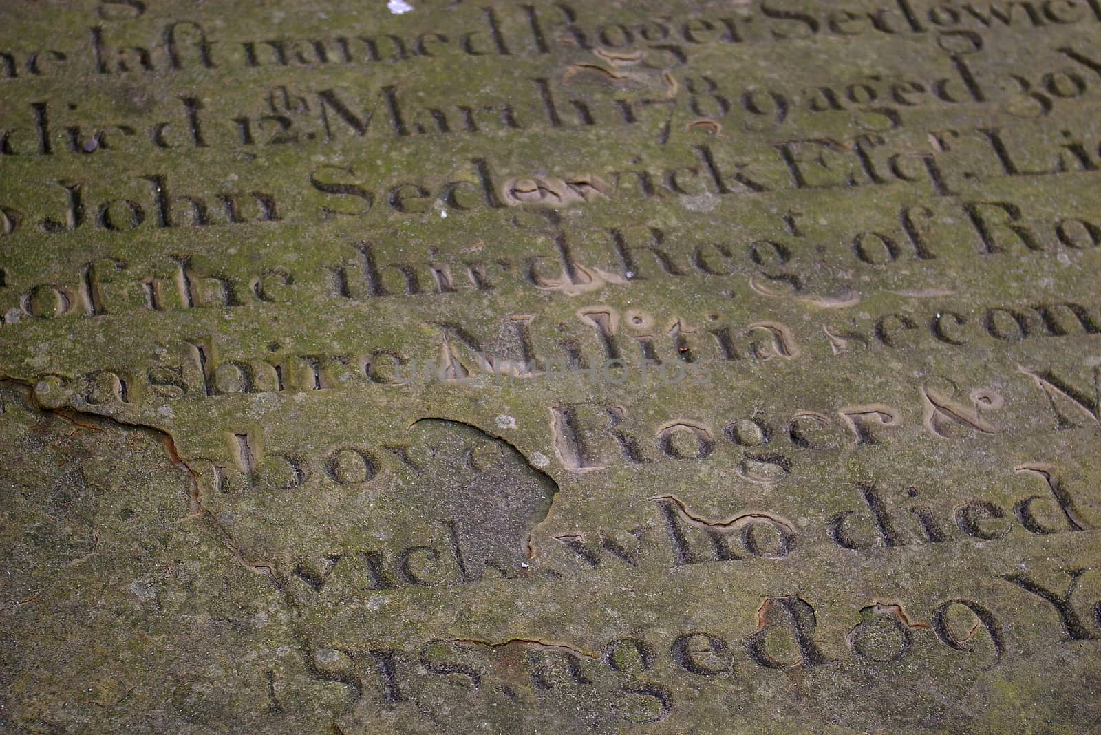 Weather-beaten old tombstone lettering in Manchester, UK
