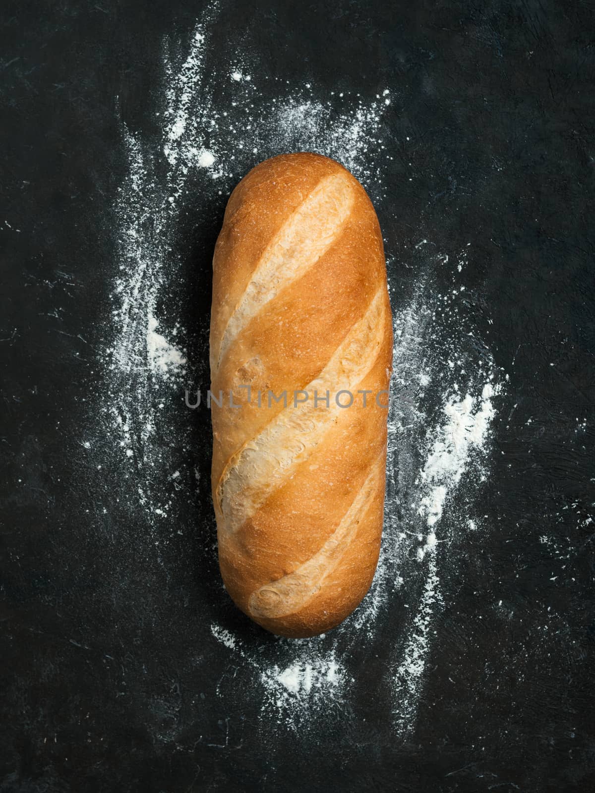 British White Bloomer or European Baton loaf bread on black background. Top view or flat lay. Copy space for text or design. Vertical.