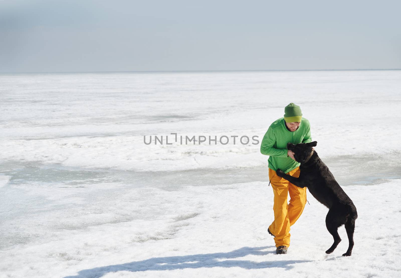 Young adult man outdoors with his dog having fun in winter lands by Novic