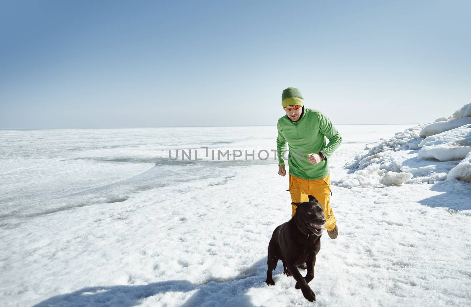 Young adult man outdoors with his dog having fun in winter lands by Novic