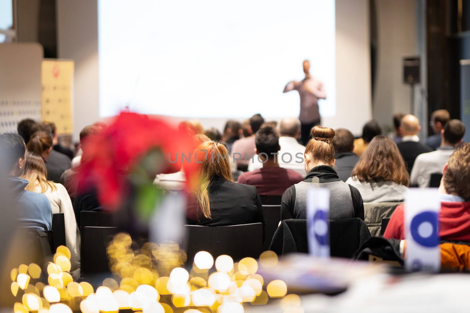 Speaker giving a talk in conference hall at business event. Rear view of unrecognizable people in audience at the conference hall. Business and entrepreneurship concept.