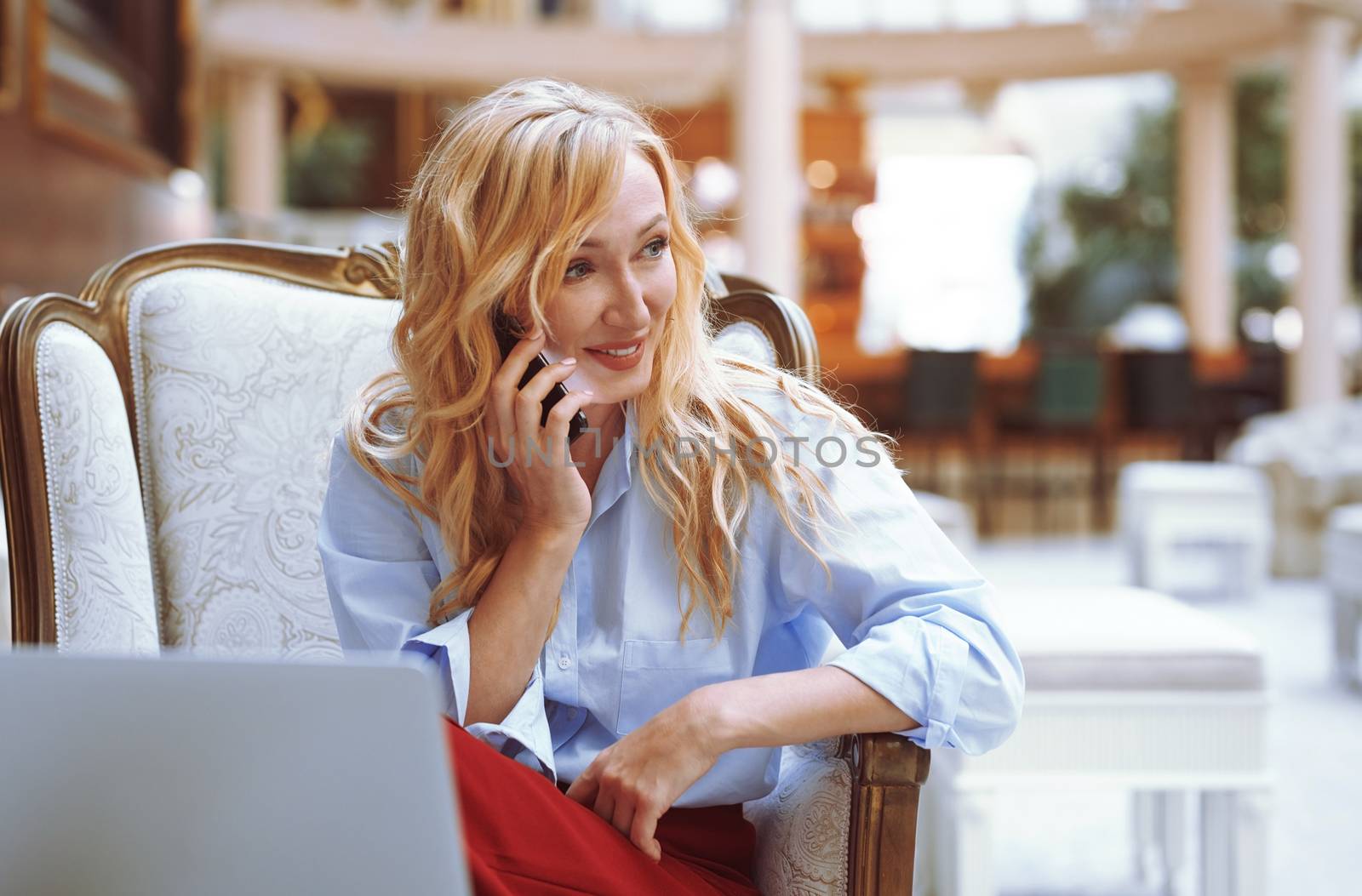 Businesswoman calling via smartphone in the modern bank lobby