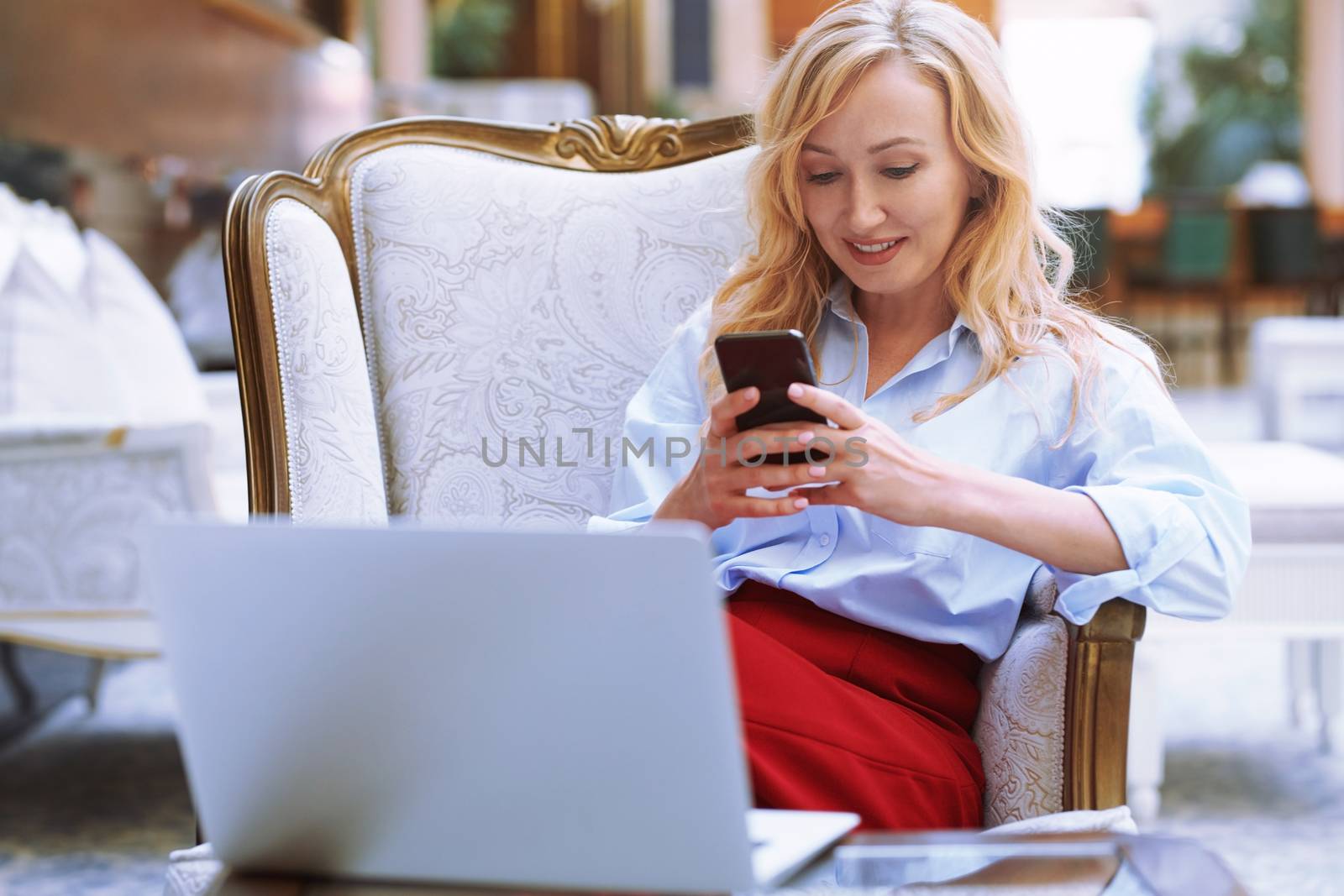 Businesswoman using smartphone in the modern bank lobby