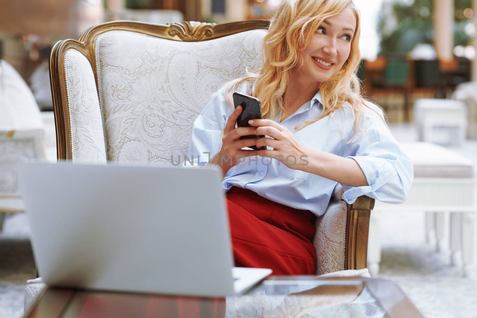 Businesswoman using smartphone in the modern bank lobby by Novic