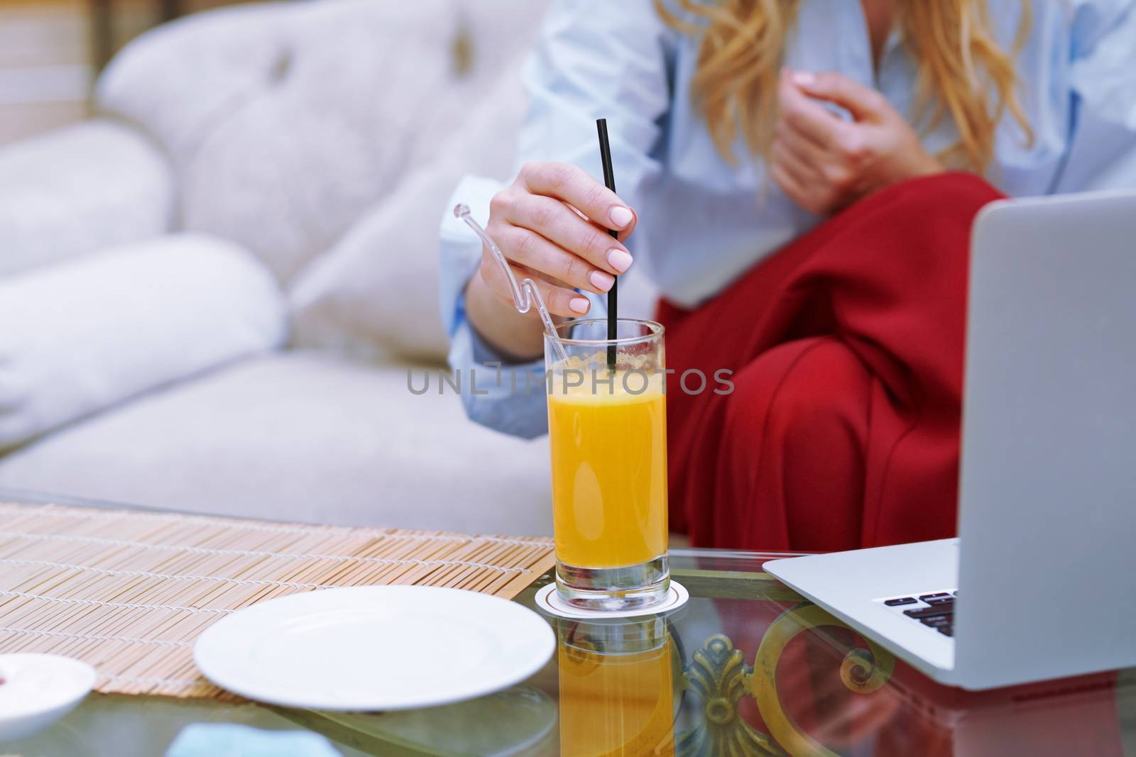 Woman relaxing at the hotel lobby and blogging via laptop by Novic